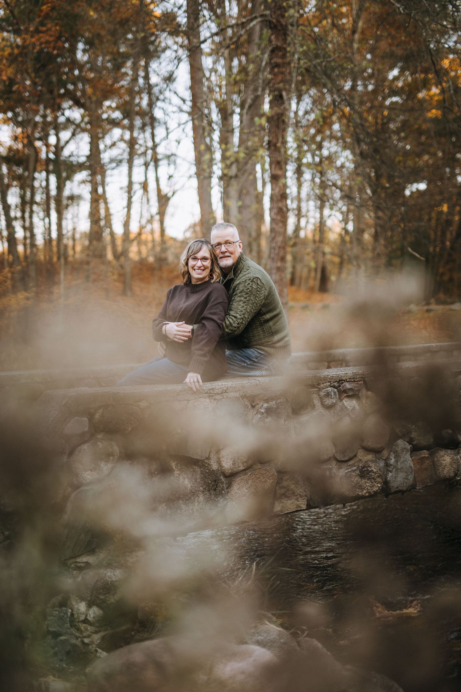 Autumn woods portrait through blurred foreground elements creating depth.
