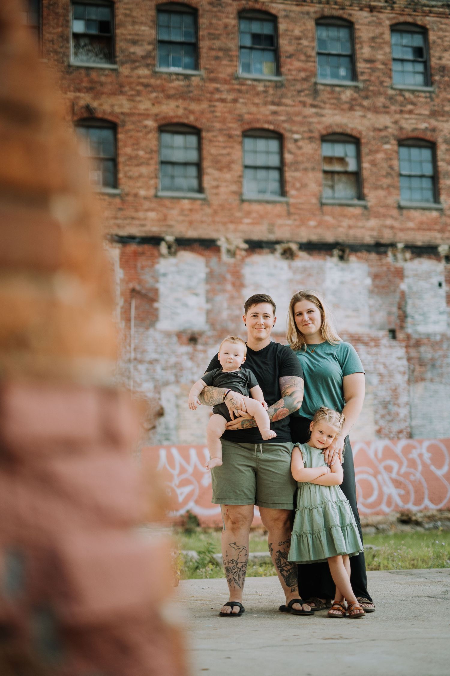 Family posing together against rustic brick wall background.