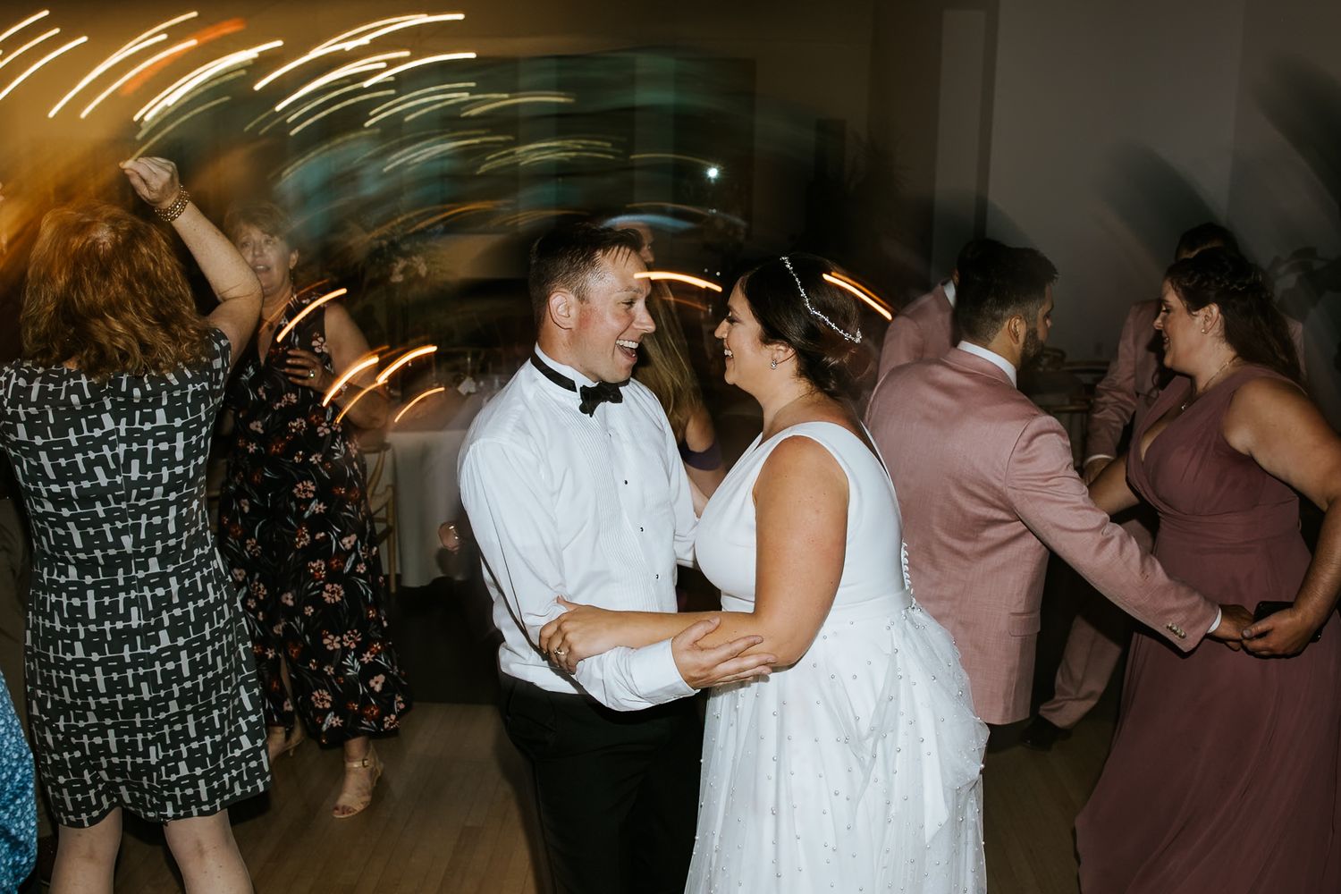 Wedding reception dance party with guests celebrating under ambient lighting.