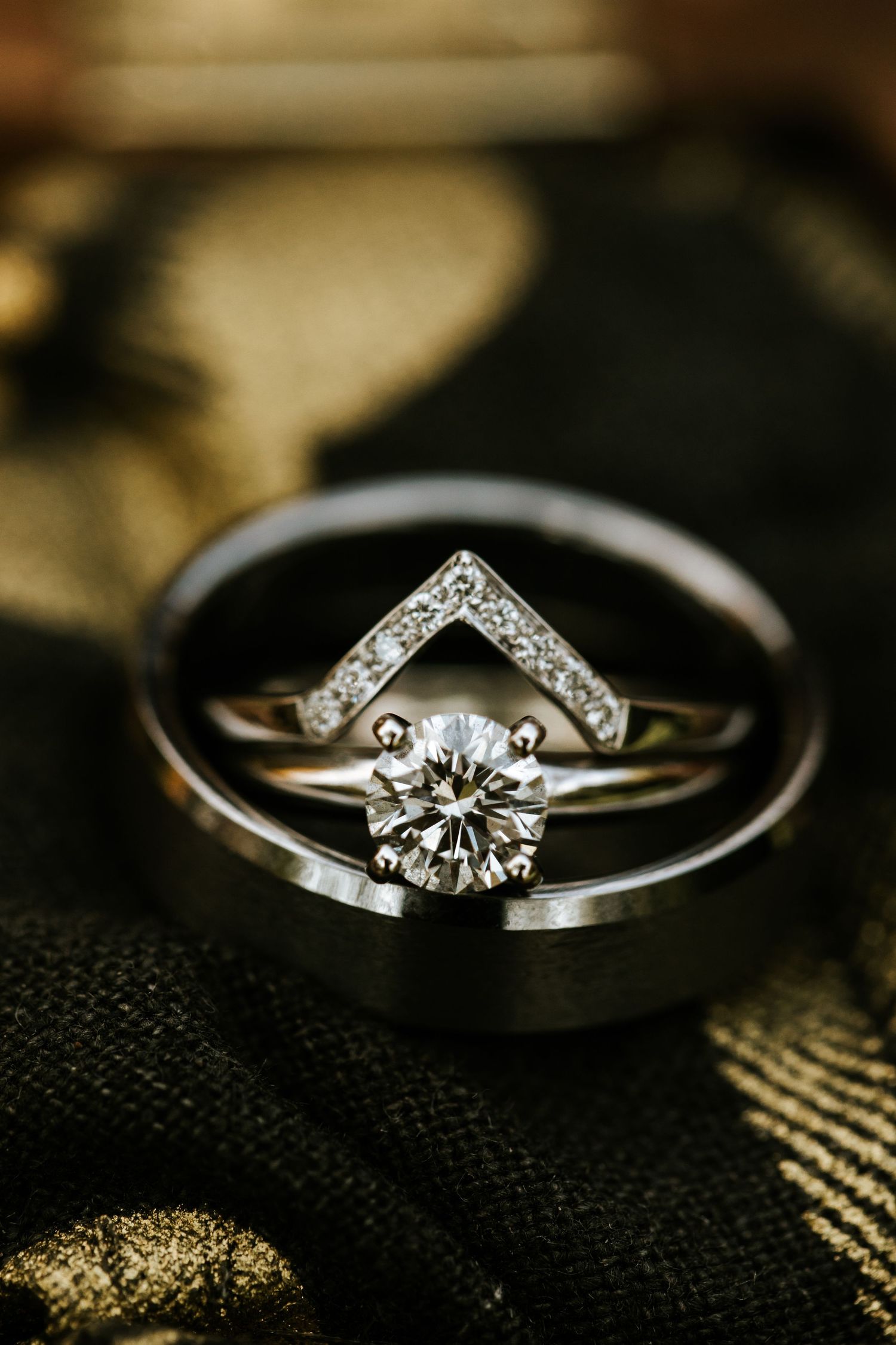 Diamond engagement ring and wedding band on dark textured surface.