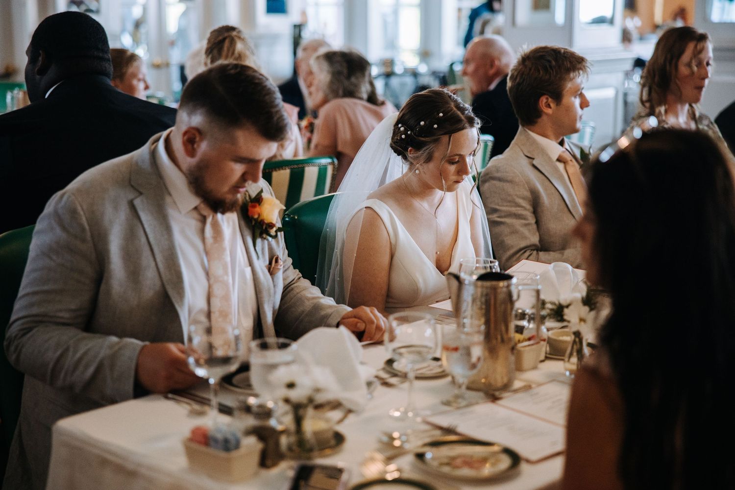 Guests seated at long dining tables during an indoor wedding reception.