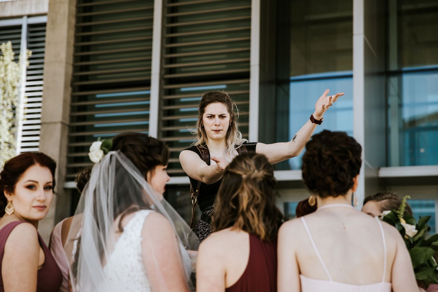 Wedding party members gathered outside a building in formal attire.