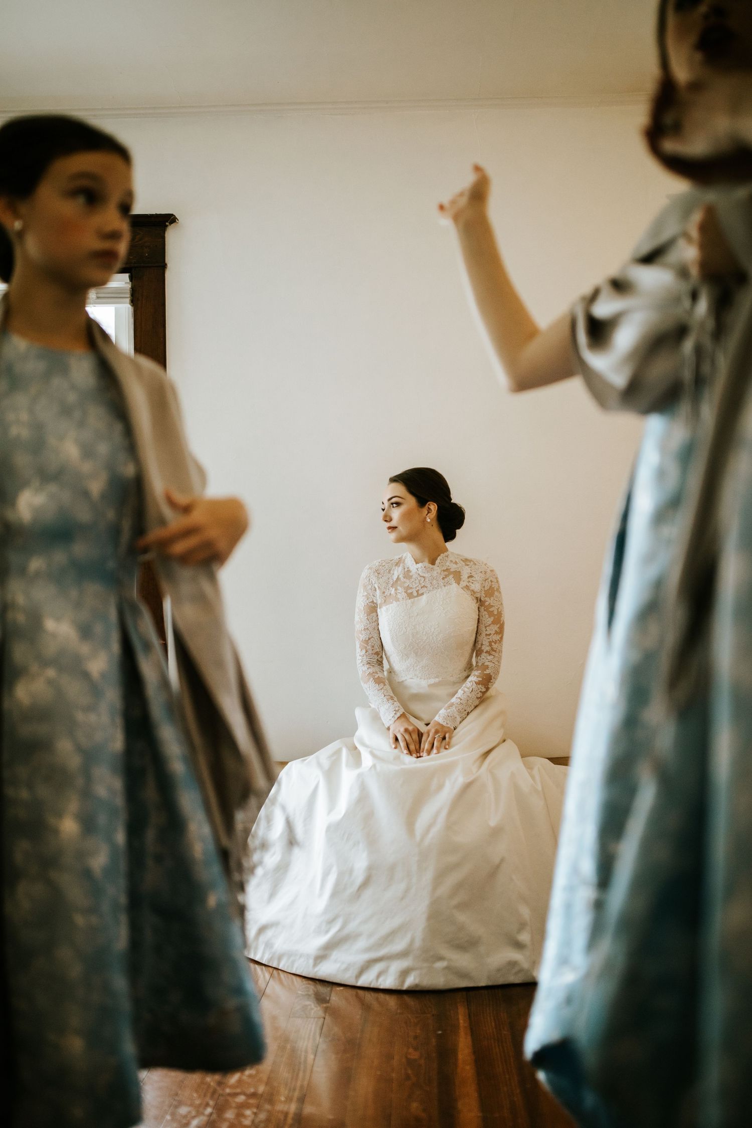 Classic white wedding dress with lace details displayed in preparation room.