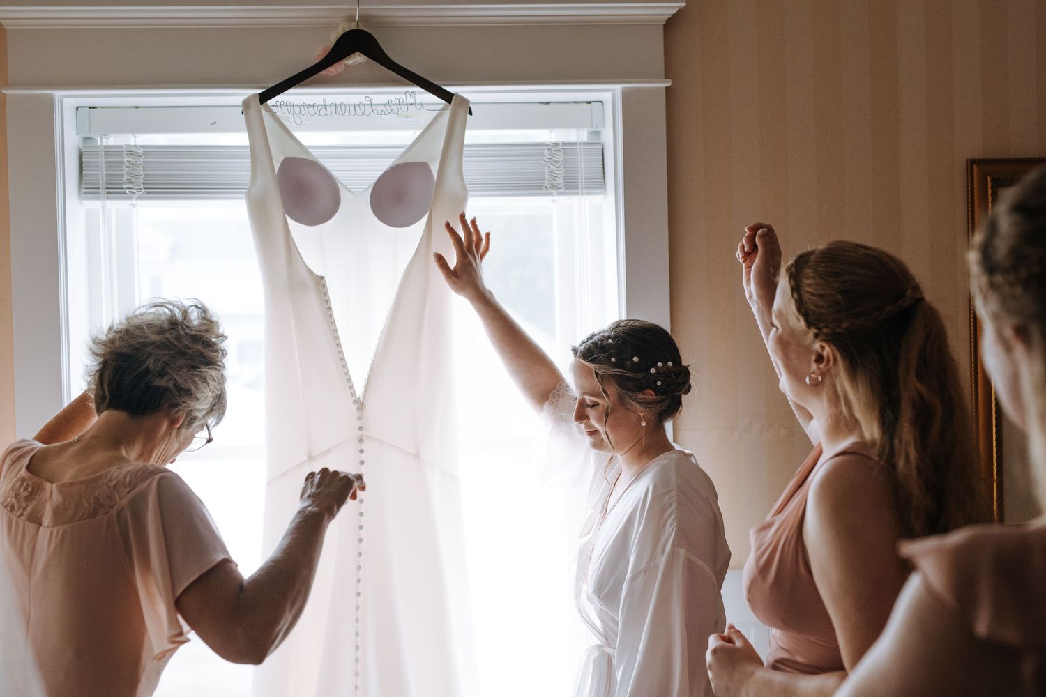 Wedding dress preparation scene with natural window light.