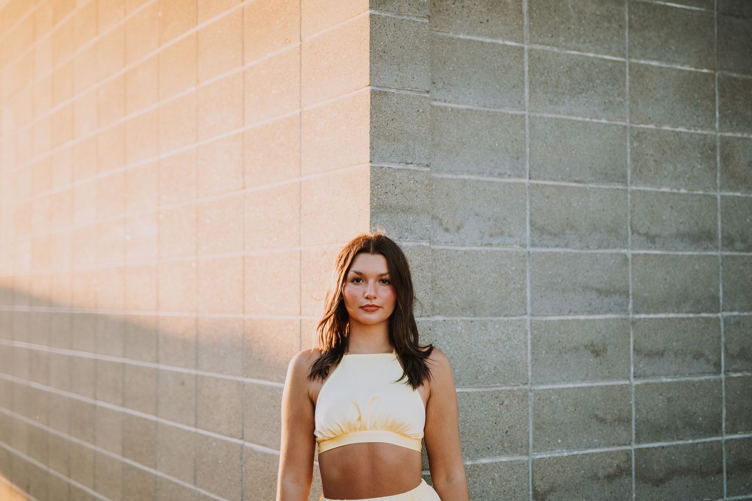 Portrait session against a concrete wall with warm sunset lighting.