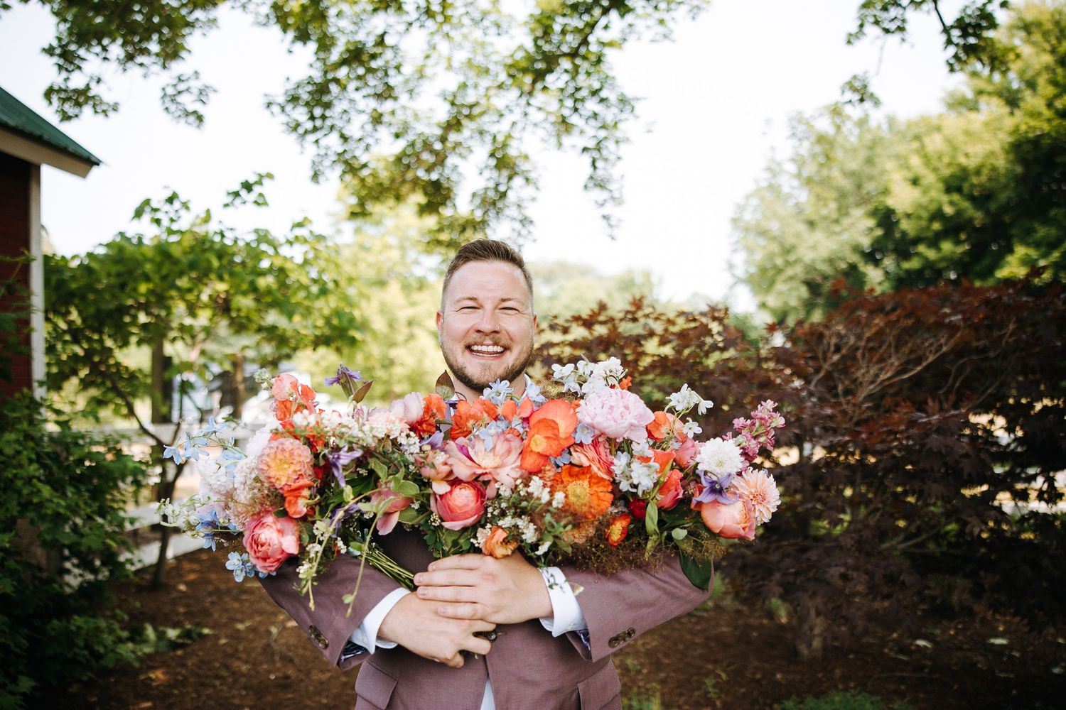 Garden wedding ceremony setup under large trees with natural greenery in the background.