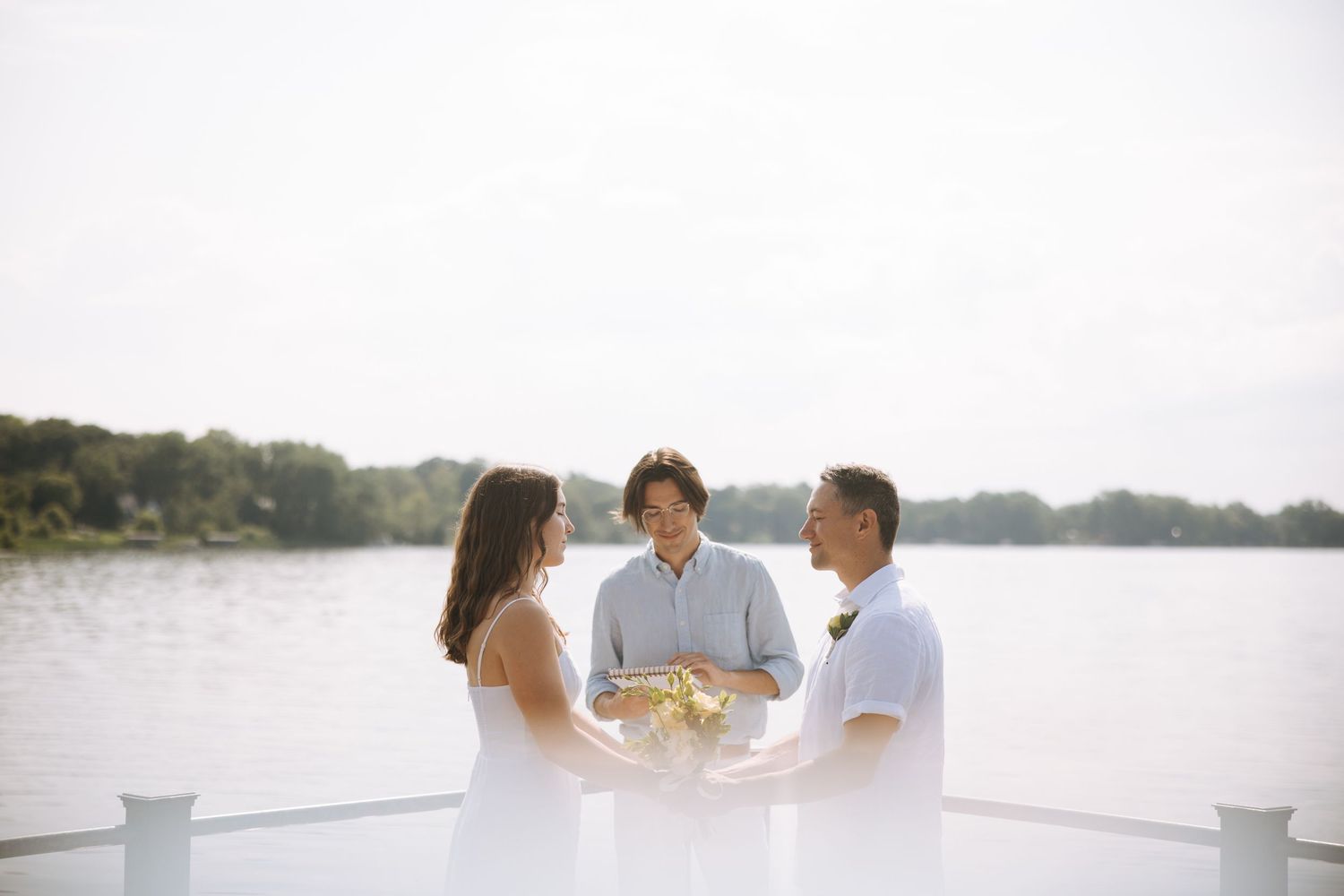 Bright outdoor waterfront engagement session with minimalist white background.
