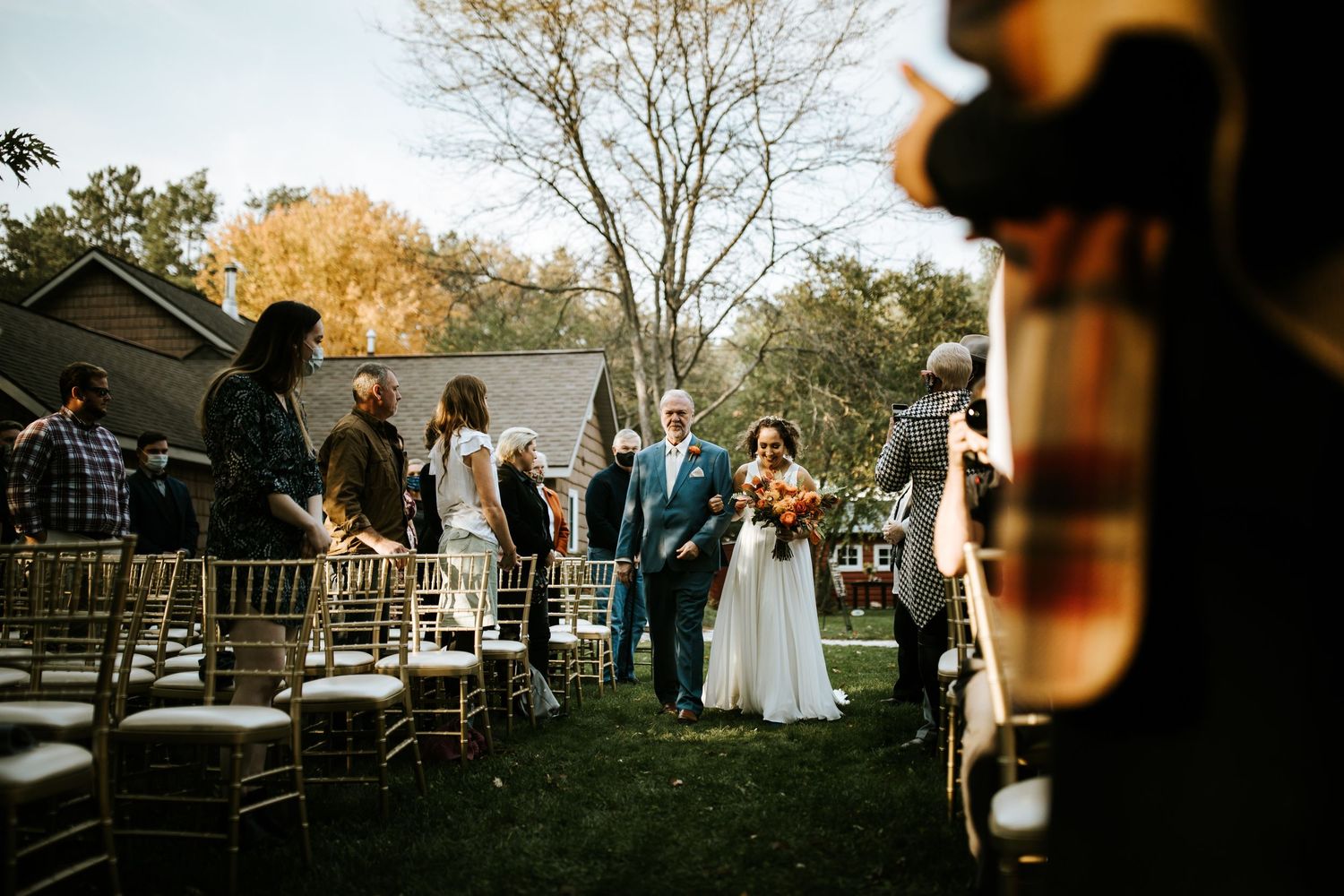 Wedding ceremony seating arranged outdoors with wooden chairs at sunset.