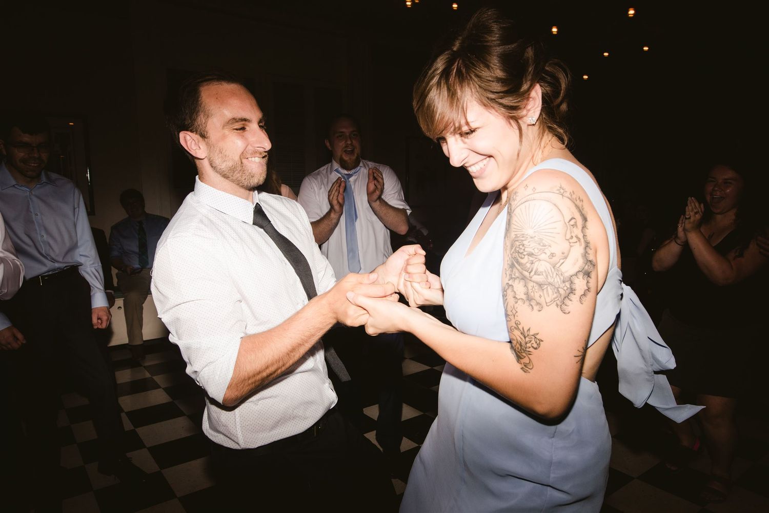 Dancing couples moving together in a dimly lit venue during an evening celebration.