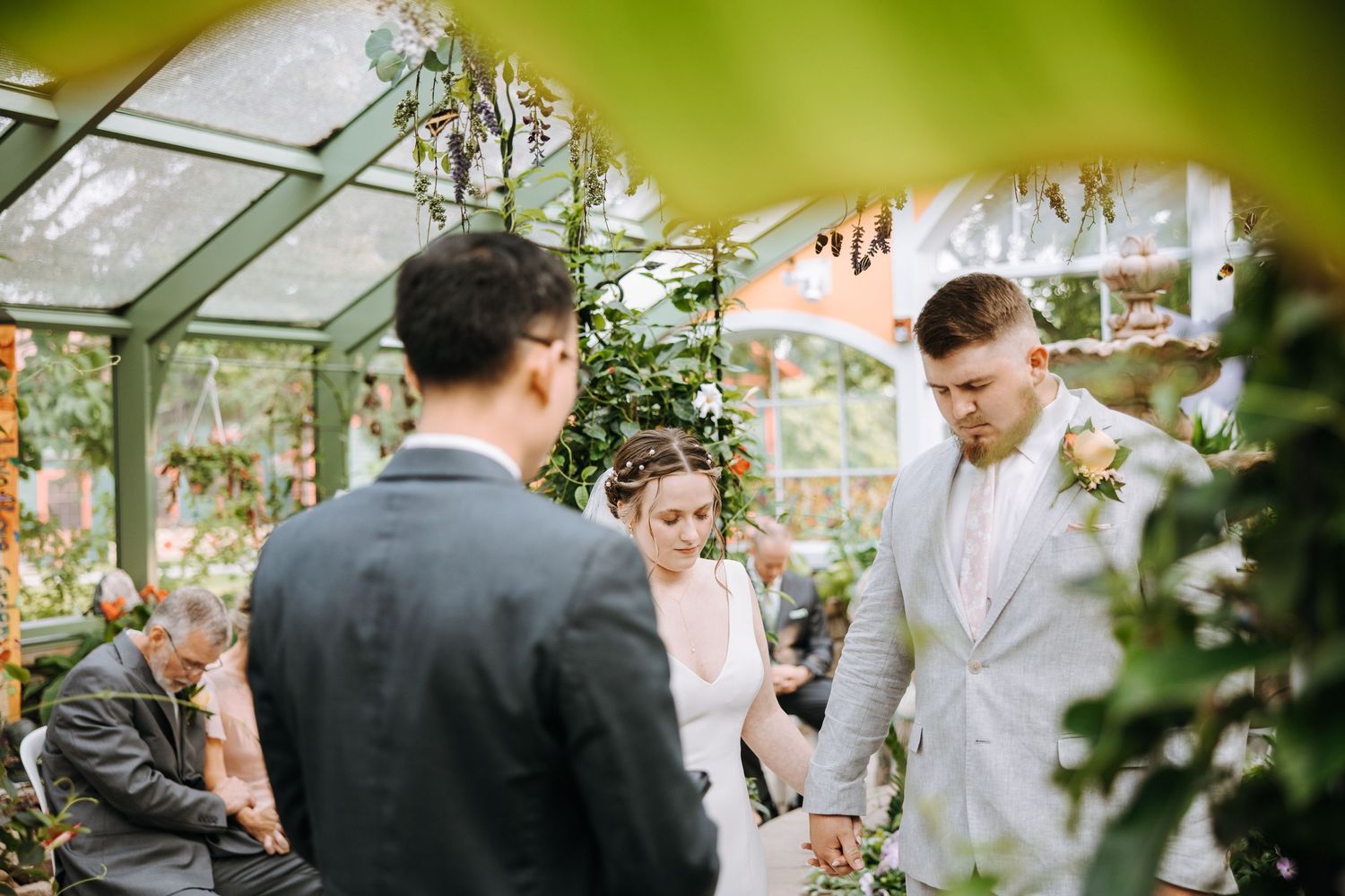 Wedding ceremony taking place in a greenhouse with natural lighting.