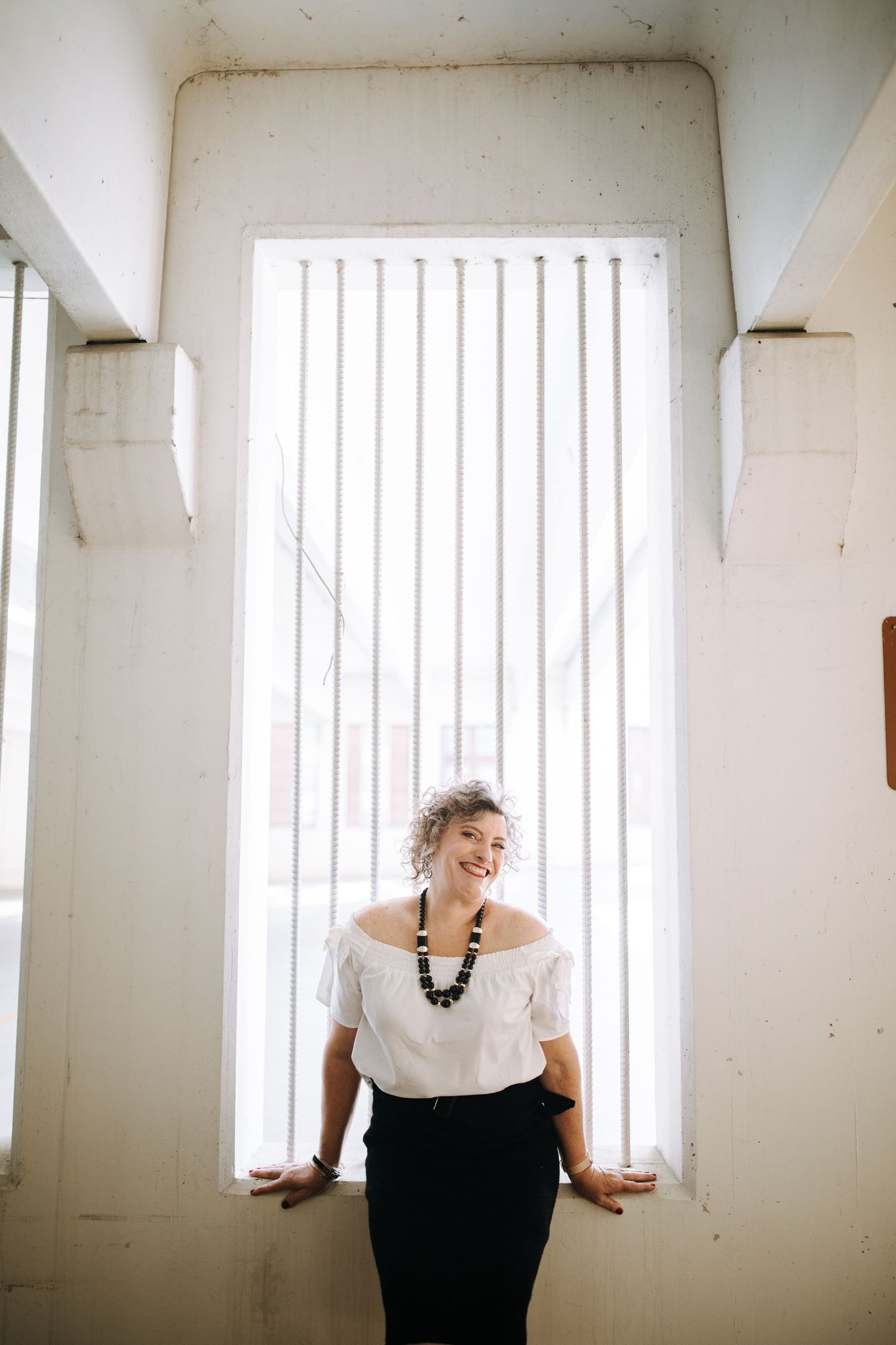 Series of artistic portraits in a white room with vertical window blinds creating dramatic lighting.