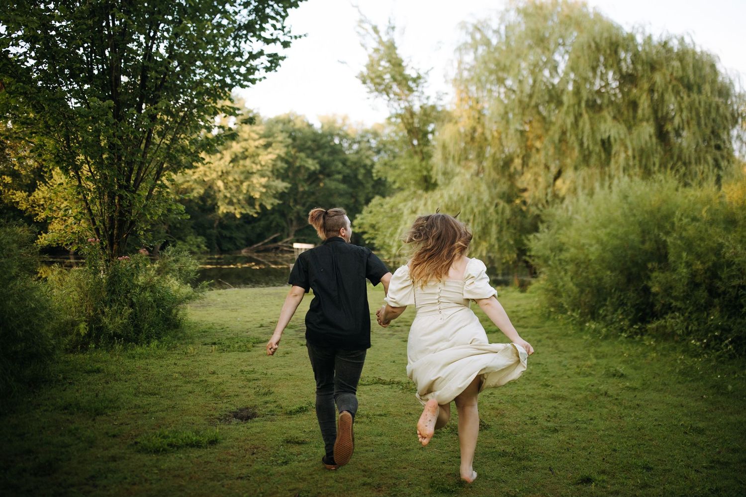 Playful couple runs and dances together in a green summer field.