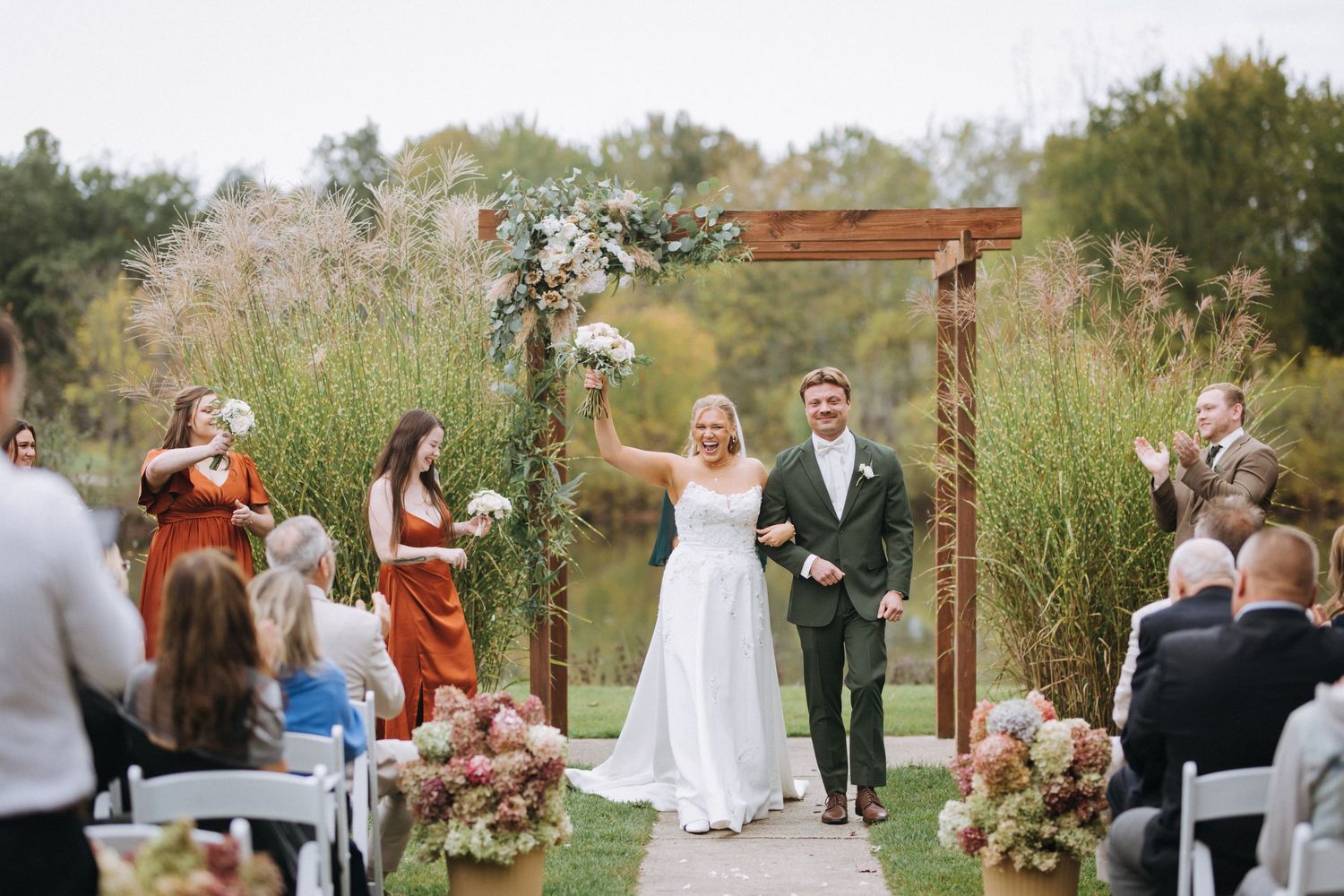 Outdoor wedding ceremony setup with white chairs and floral arrangements.