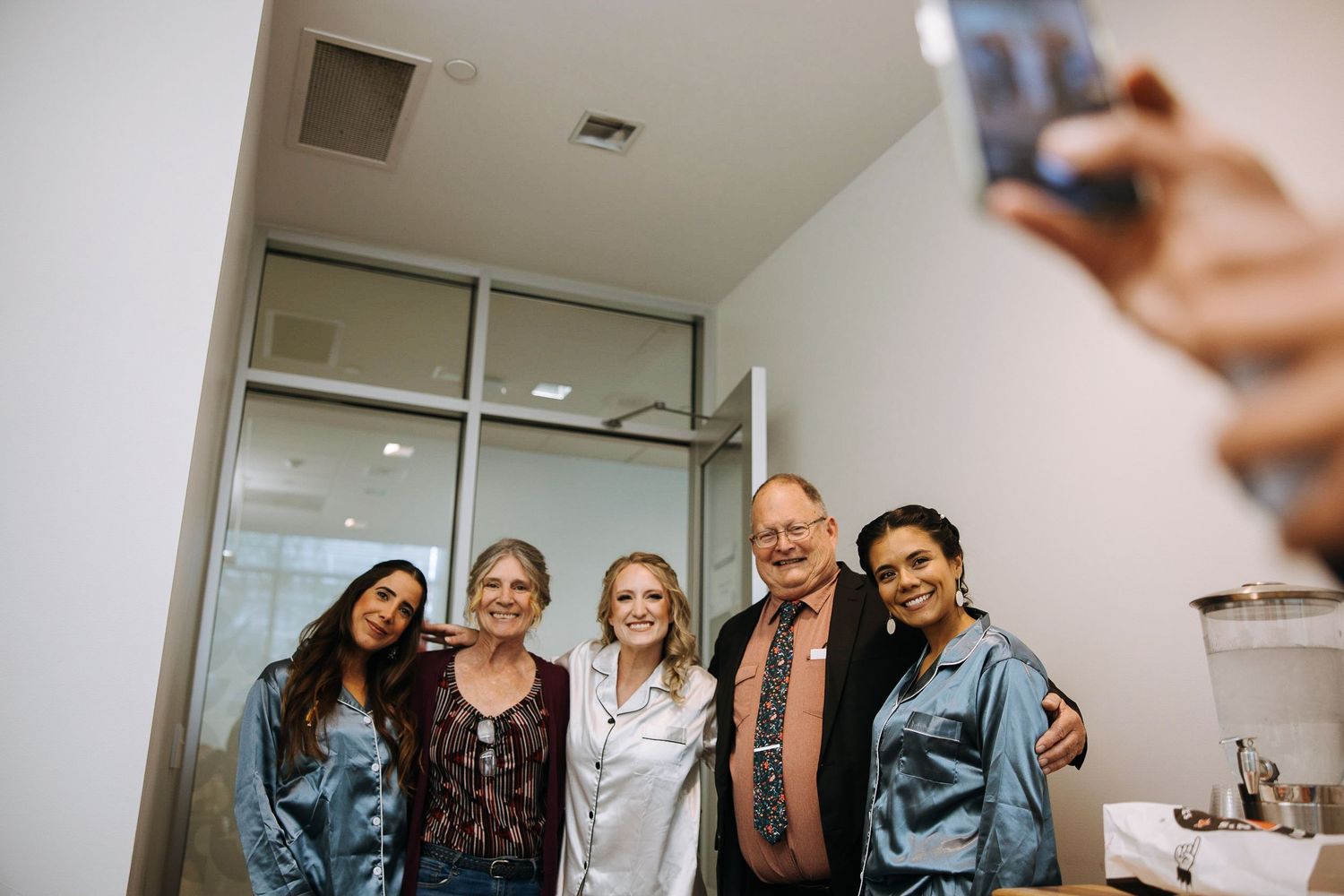 Group poses together for casual selfie photo in bright indoor setting.
