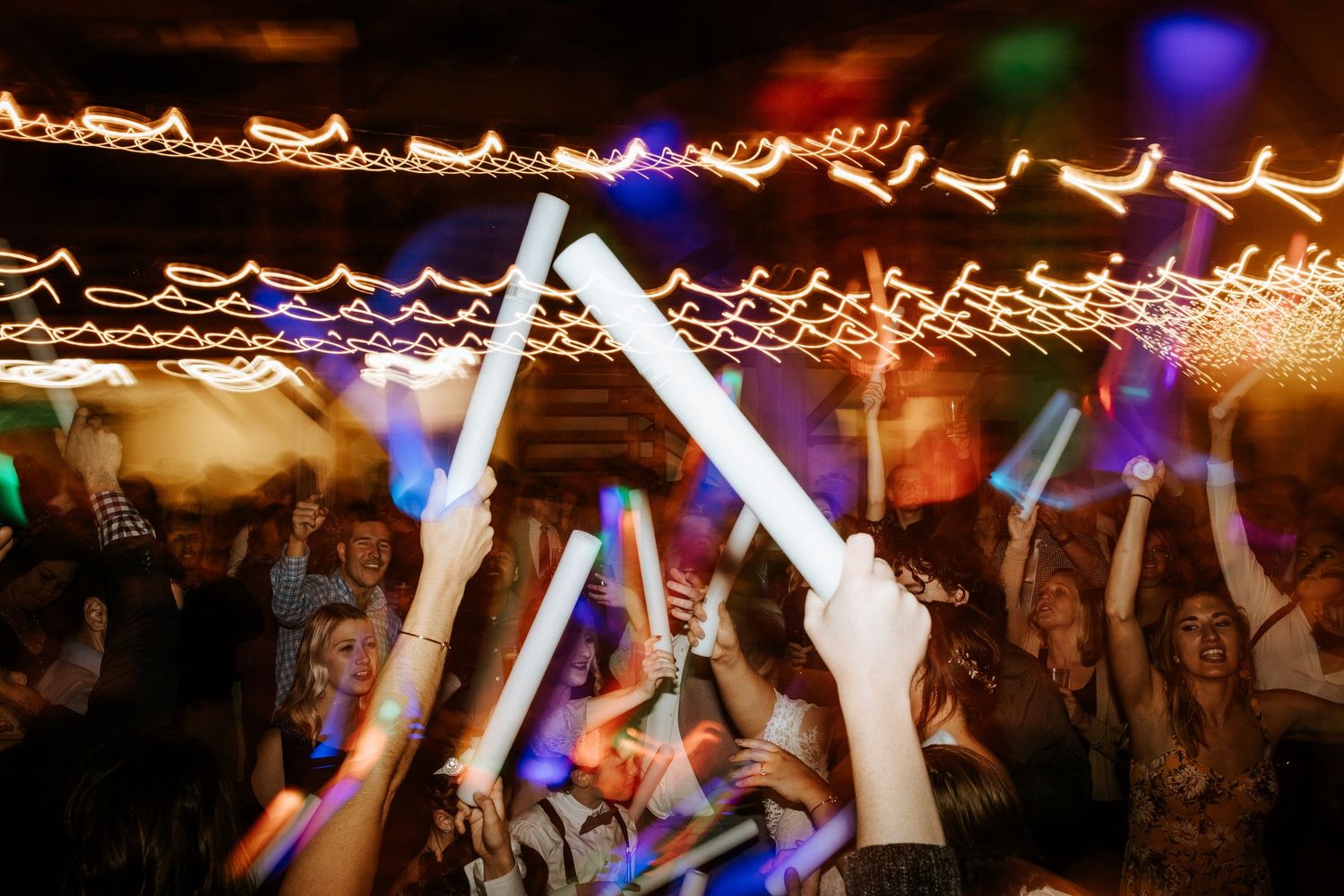 Dance floor filled with celebration under string lights at evening reception.