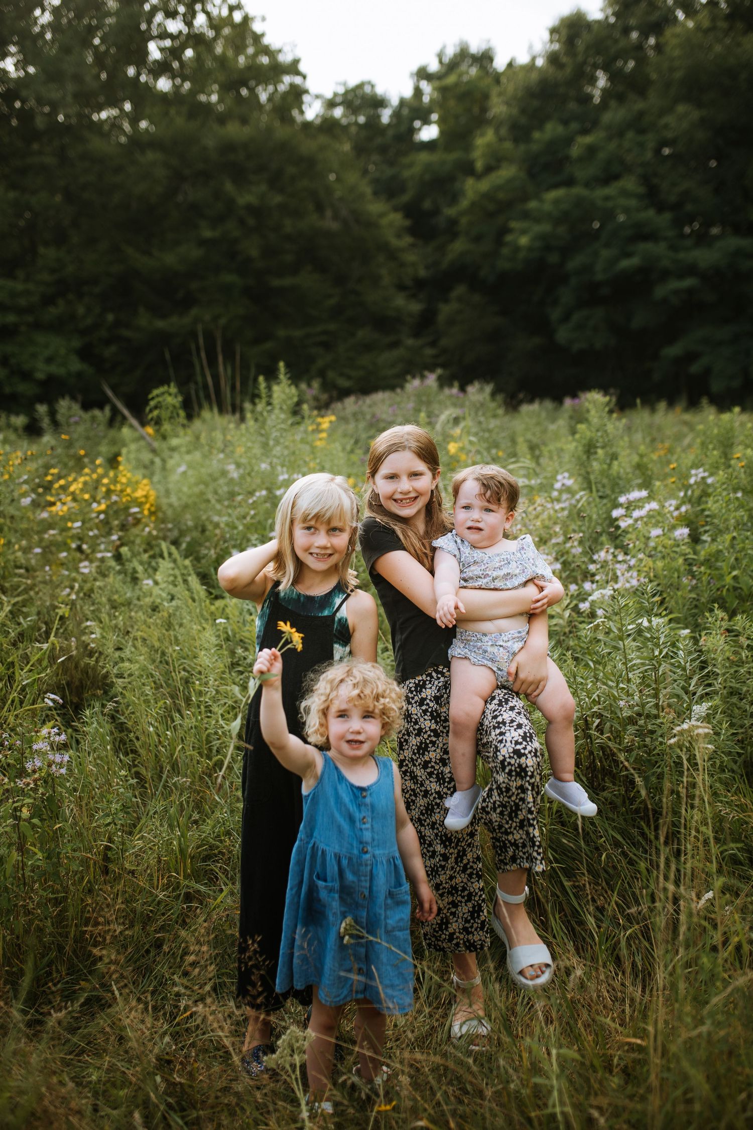 Family enjoying a playful moment together in a wildflower meadow on a sunny day.