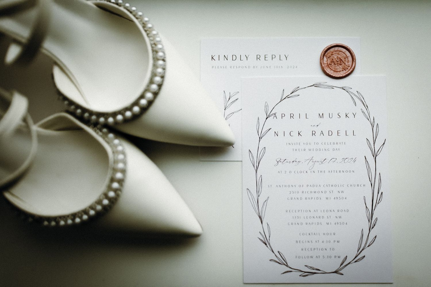 Elegant wedding invitation with botanical wreath design and wax seal.