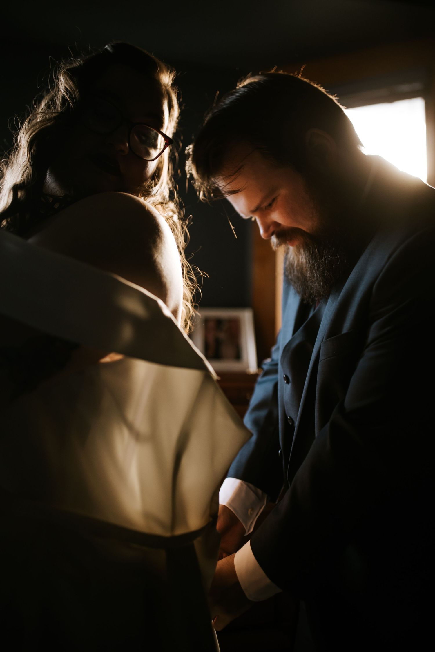 A silhouetted couple shares an intimate moment in dramatic window lighting.