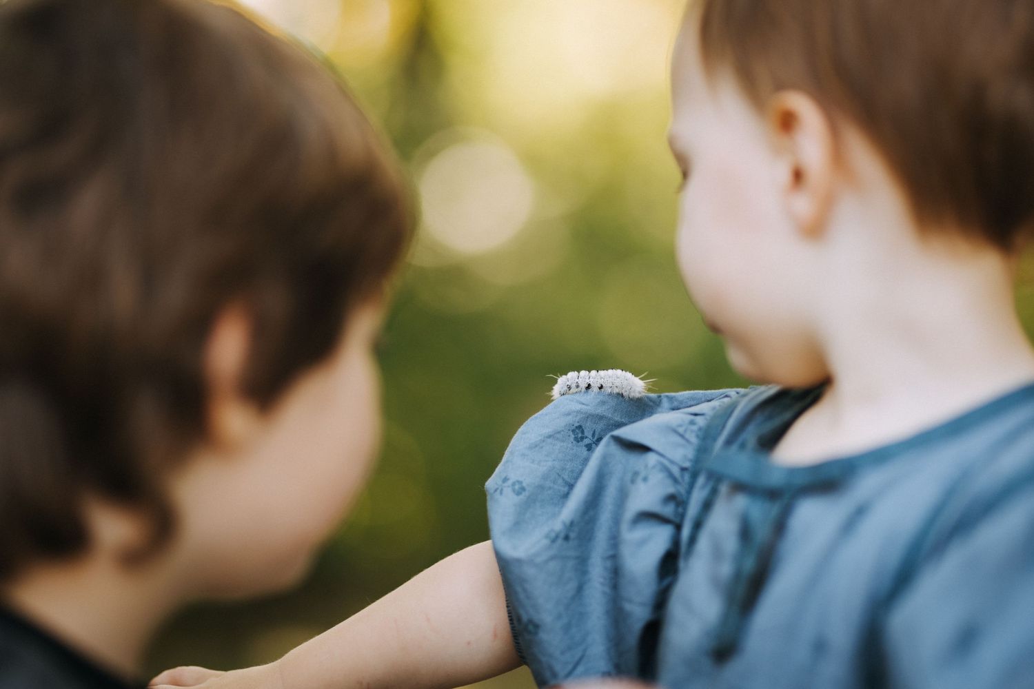 Two children share a close moment together outdoors in natural lighting.