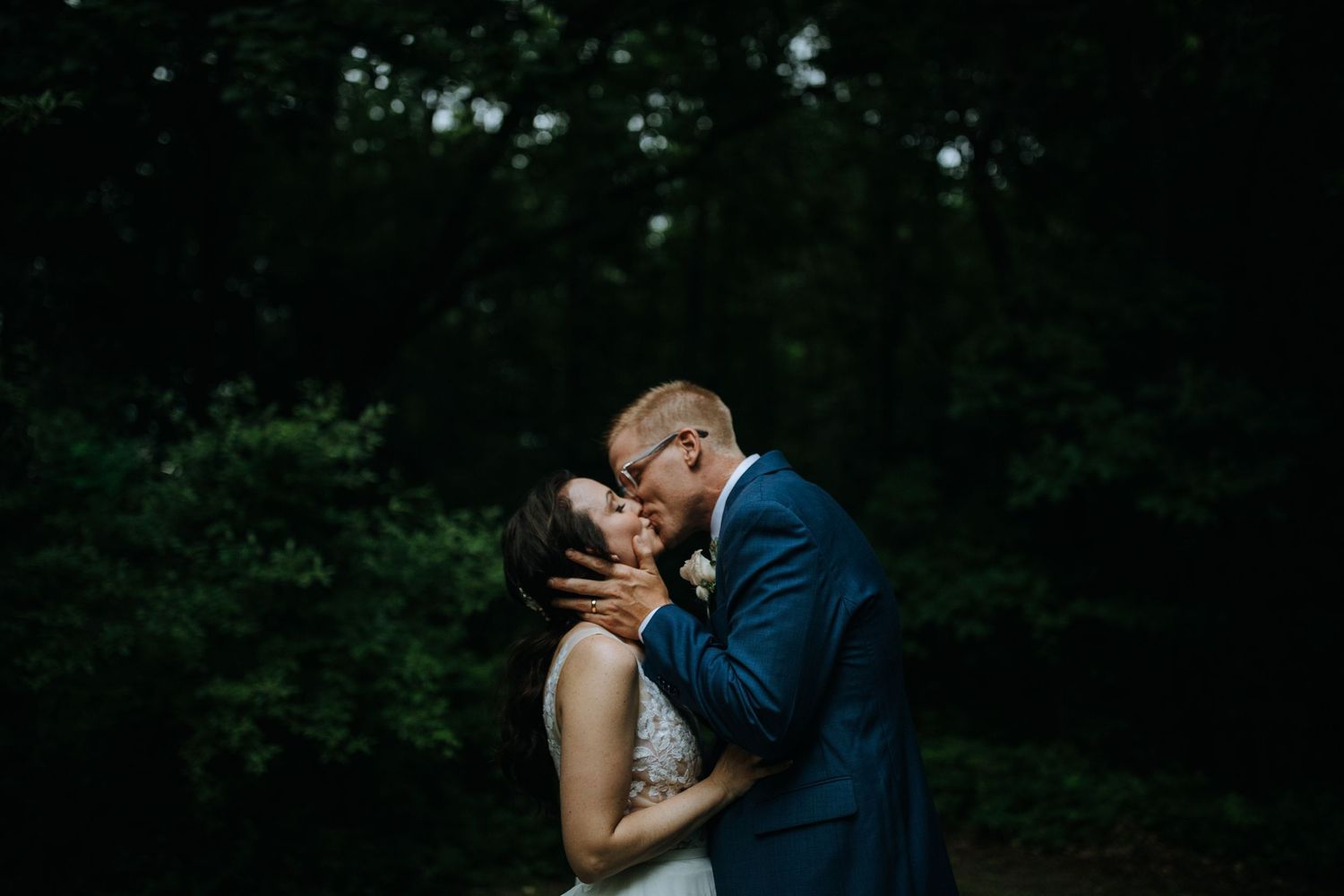 Romantic sunset silhouettes of a couple embracing in a wooded outdoor setting.