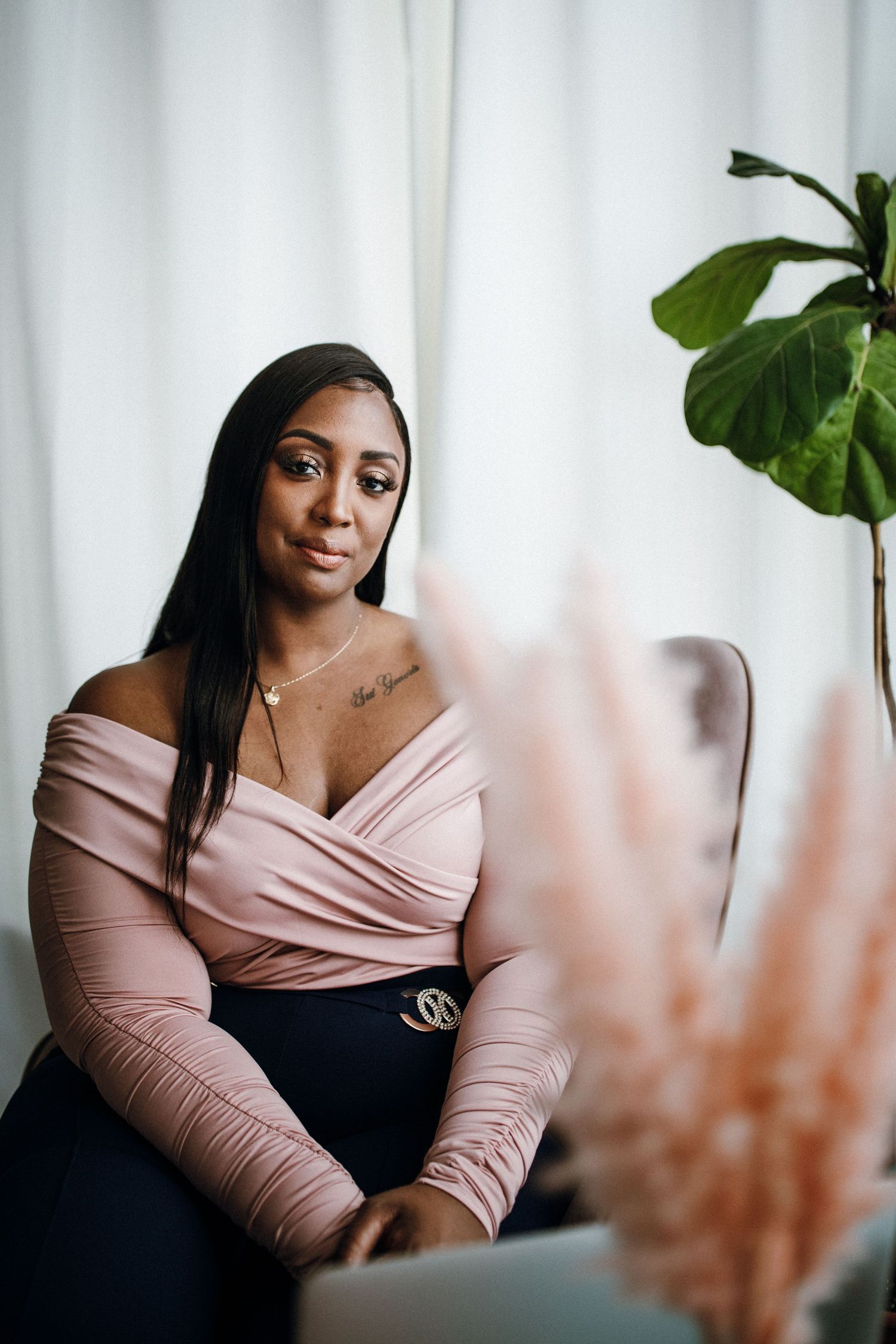 Elegant portrait series featuring soft pink wrap top and dark outfit against white curtained background.