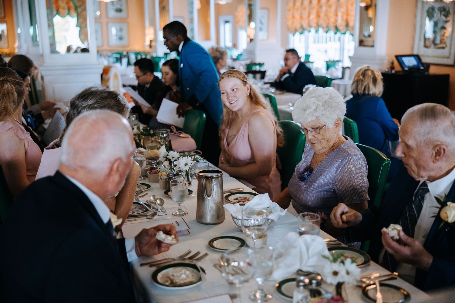 Wedding reception guests enjoying dinner at elegantly set tables.