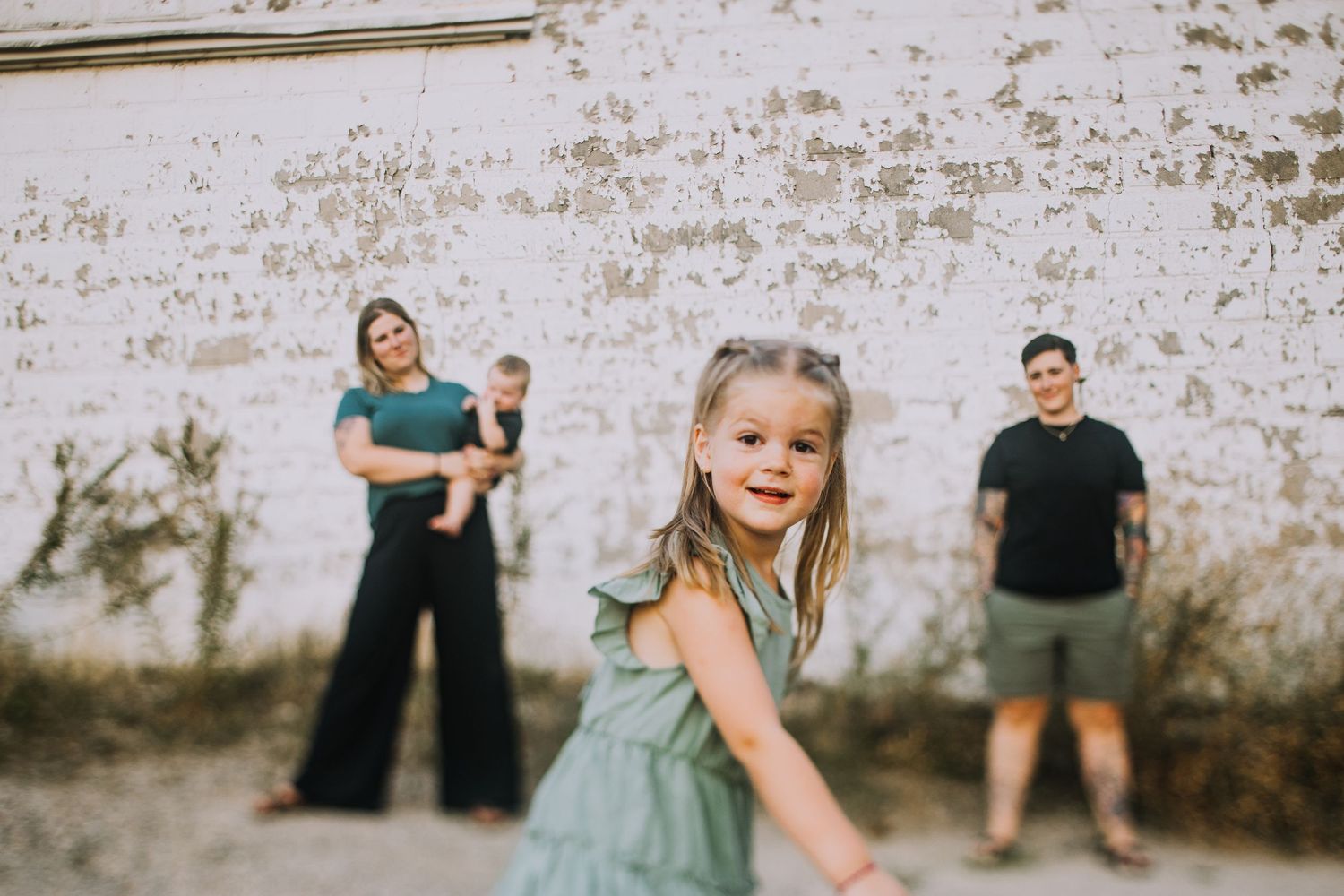 Family walking together near industrial brick building.