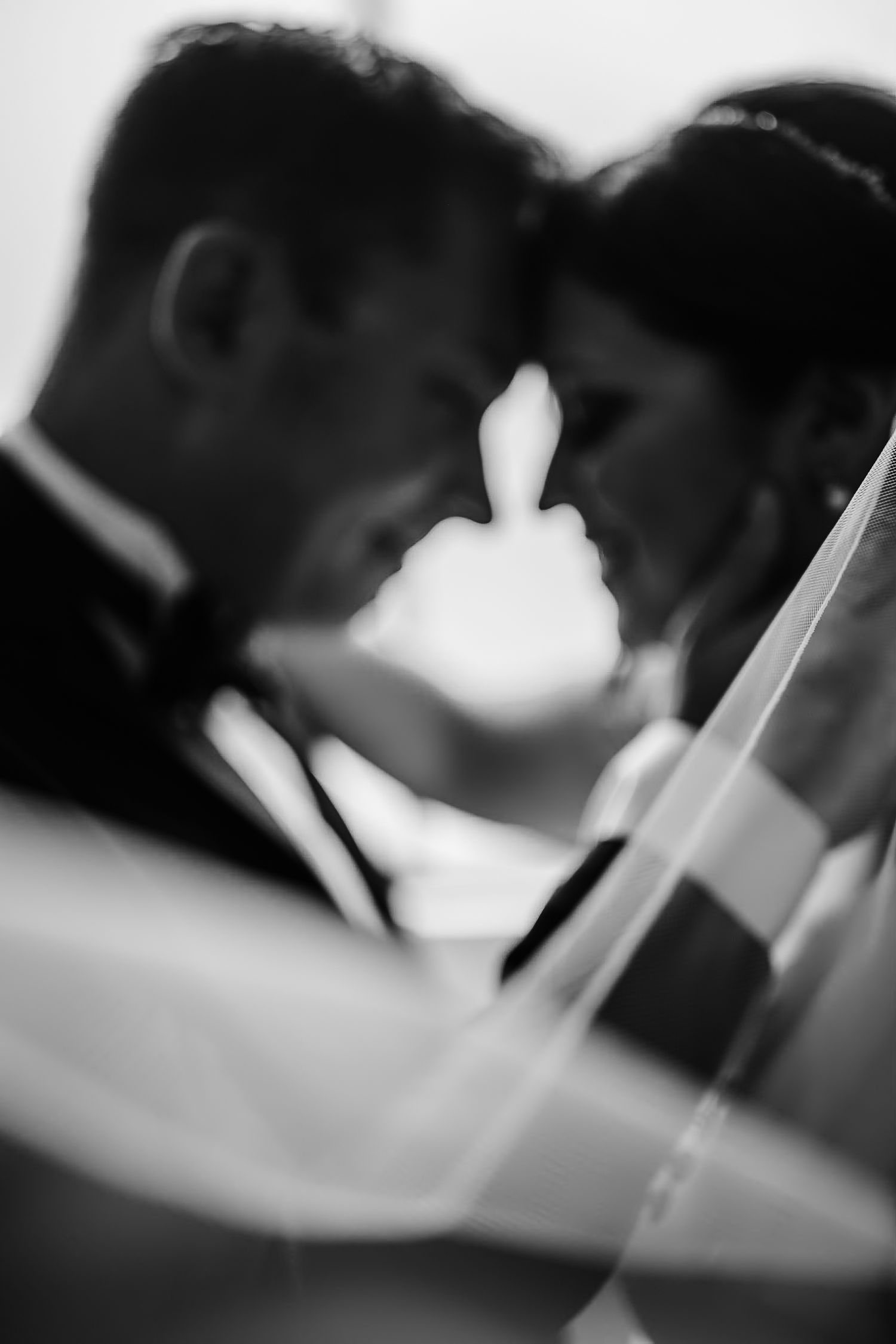 Intimate black and white portrait of a romantic moment through a wedding veil.