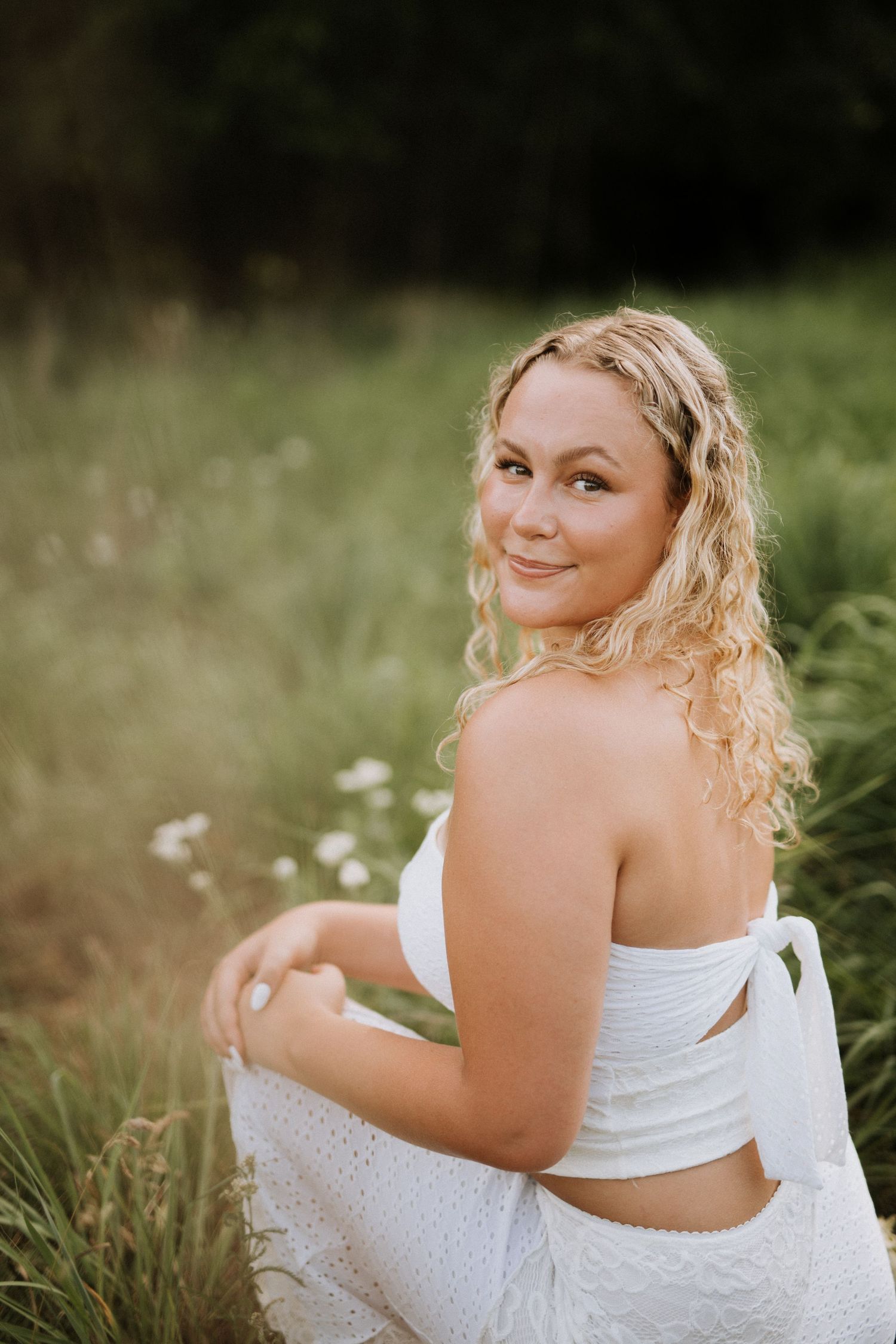 Person in white dress poses gracefully in a field of wildflowers.