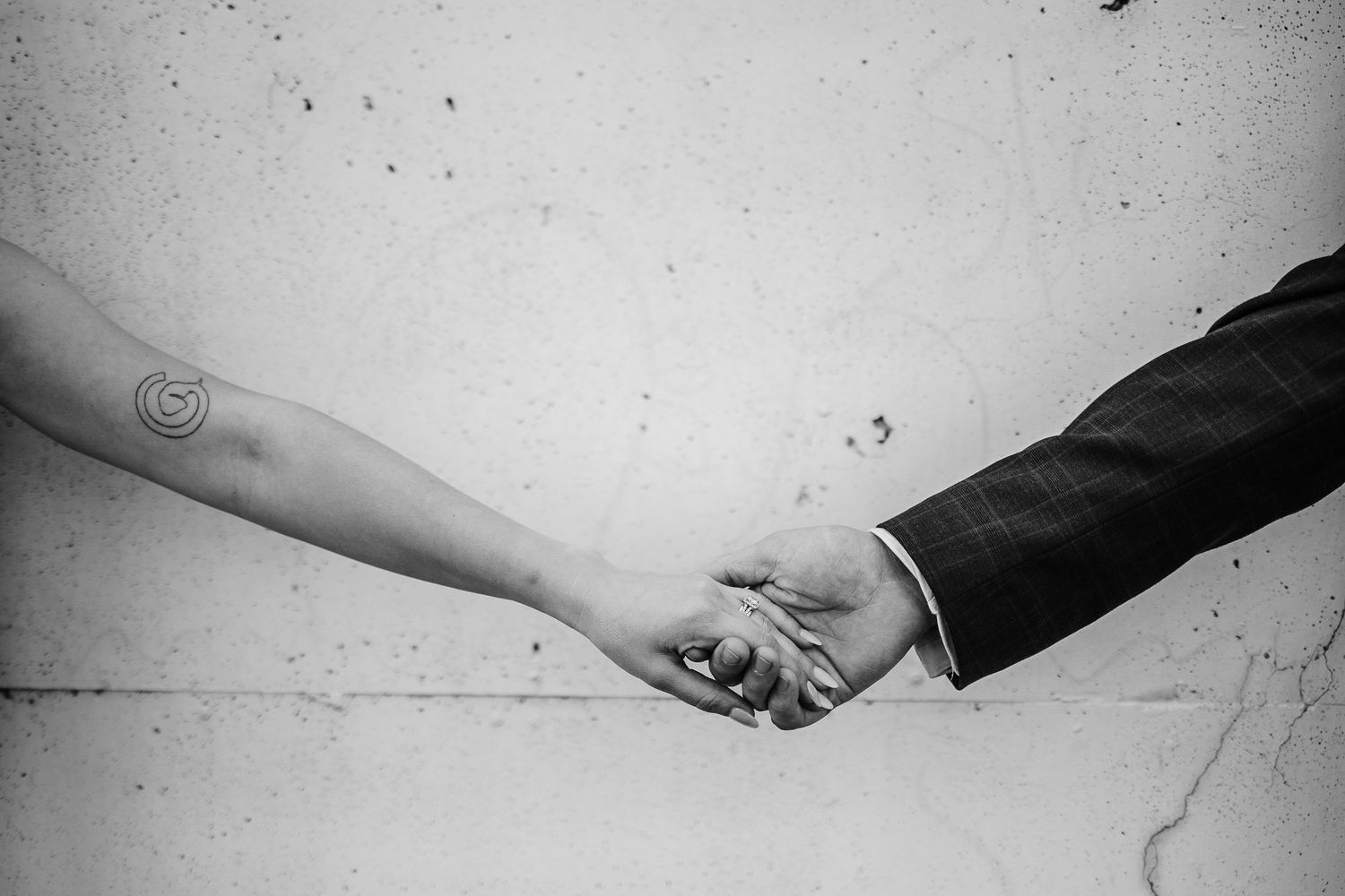 Black and white close-up of hands reaching toward each other in romantic gesture.