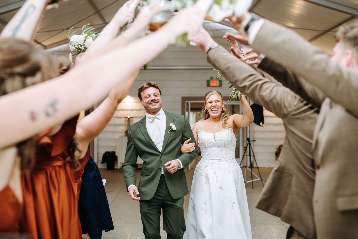 Wedding party forms celebratory tunnel for newlyweds to walk through.