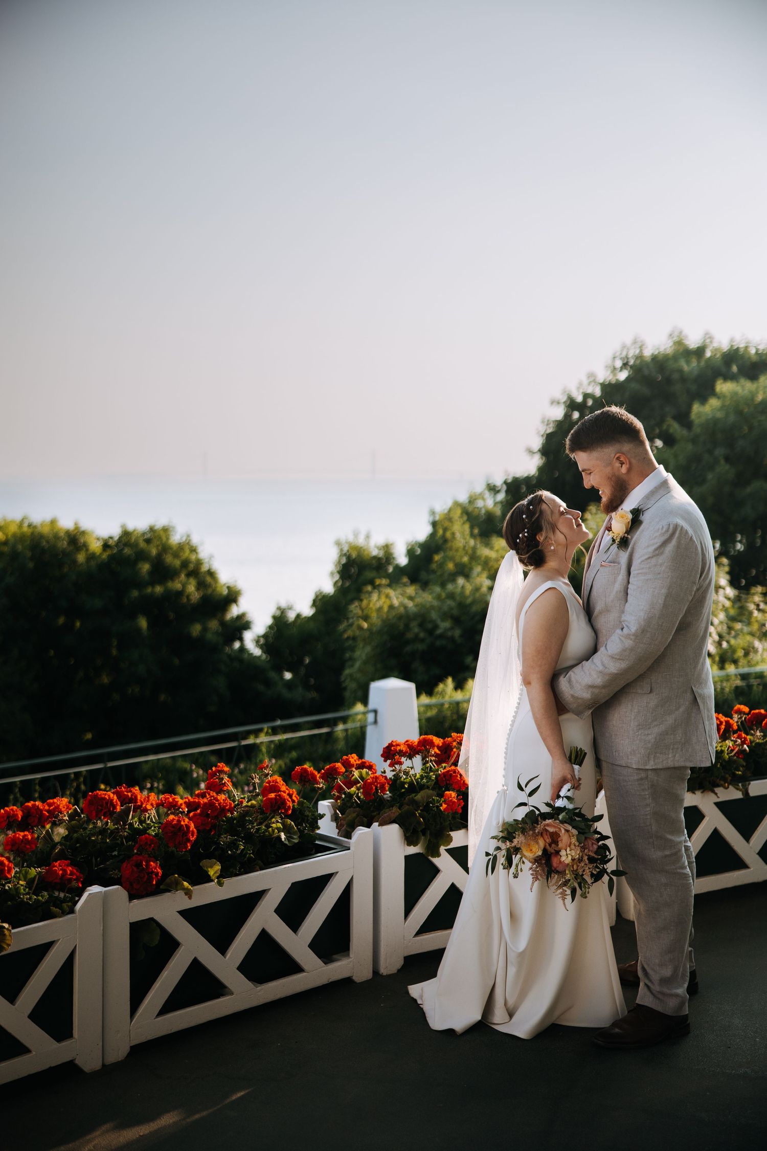 Romantic sunset moment on a balcony decorated with red flowers and white railings.