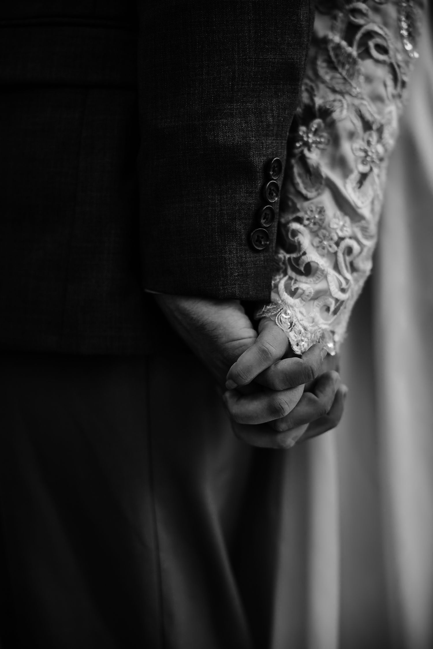 Artistic black and white detail shot of delicate lace on a wedding dress sleeve.
