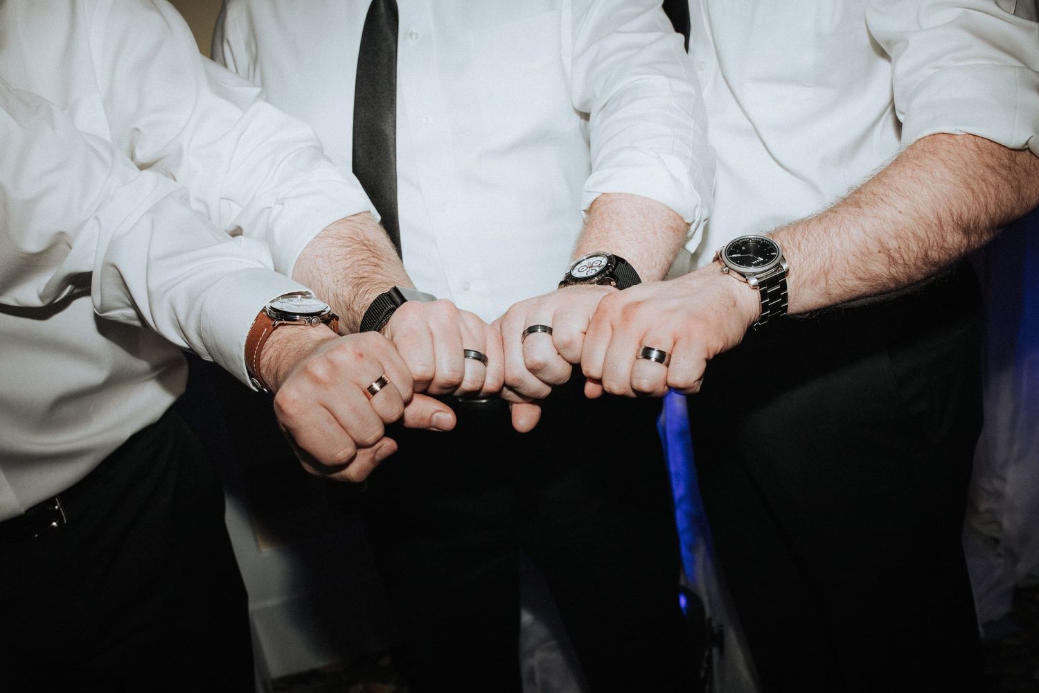 Close-up of hands in white dress shirts linked together in a line.