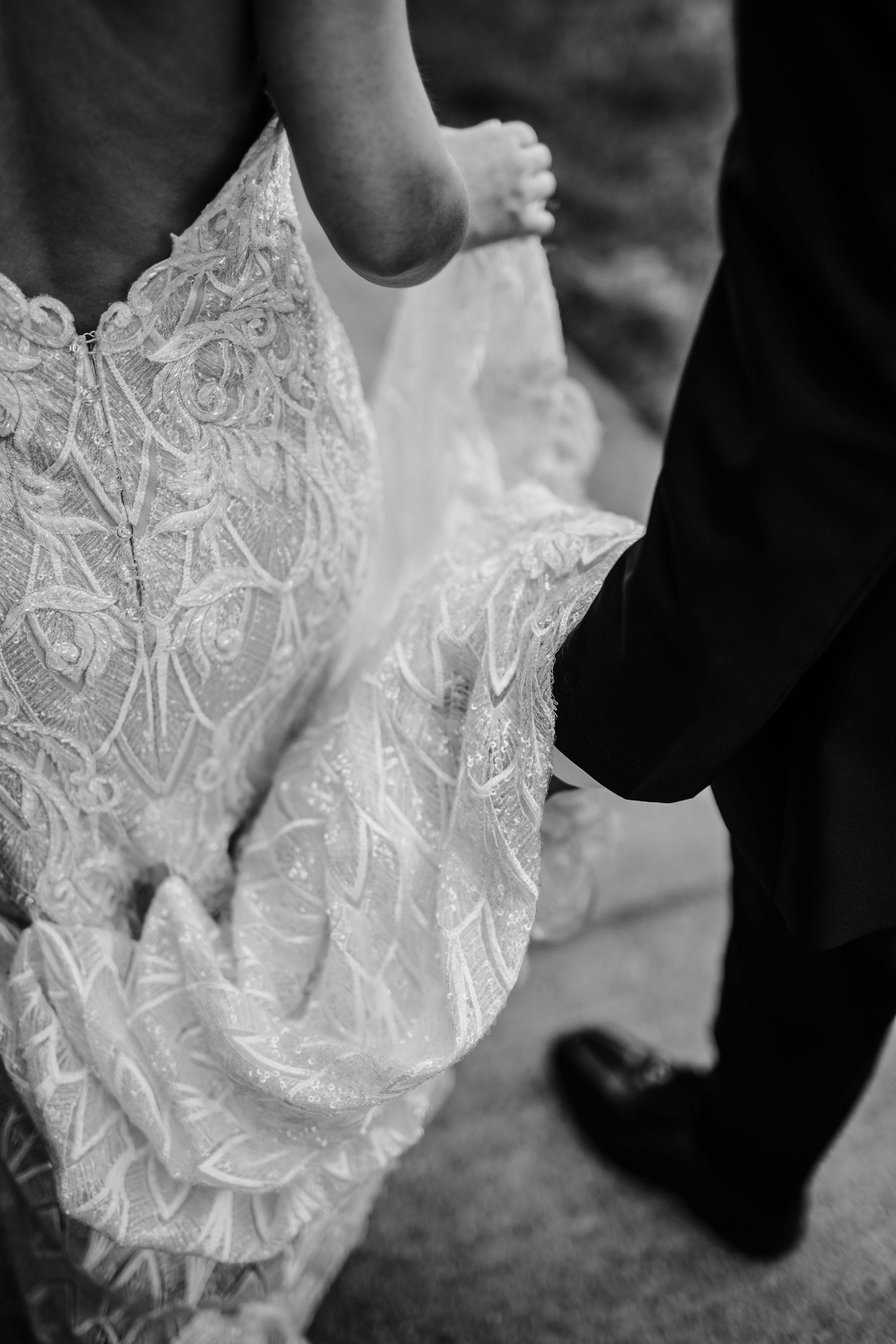 Close-up detail of intricate lace wedding dress and formal shoes.