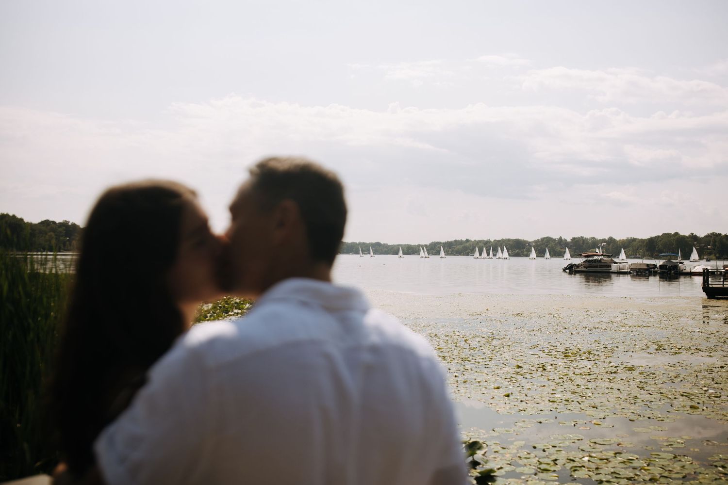 A romantic sunset scene by the water with boats dotting the harbor in the background.