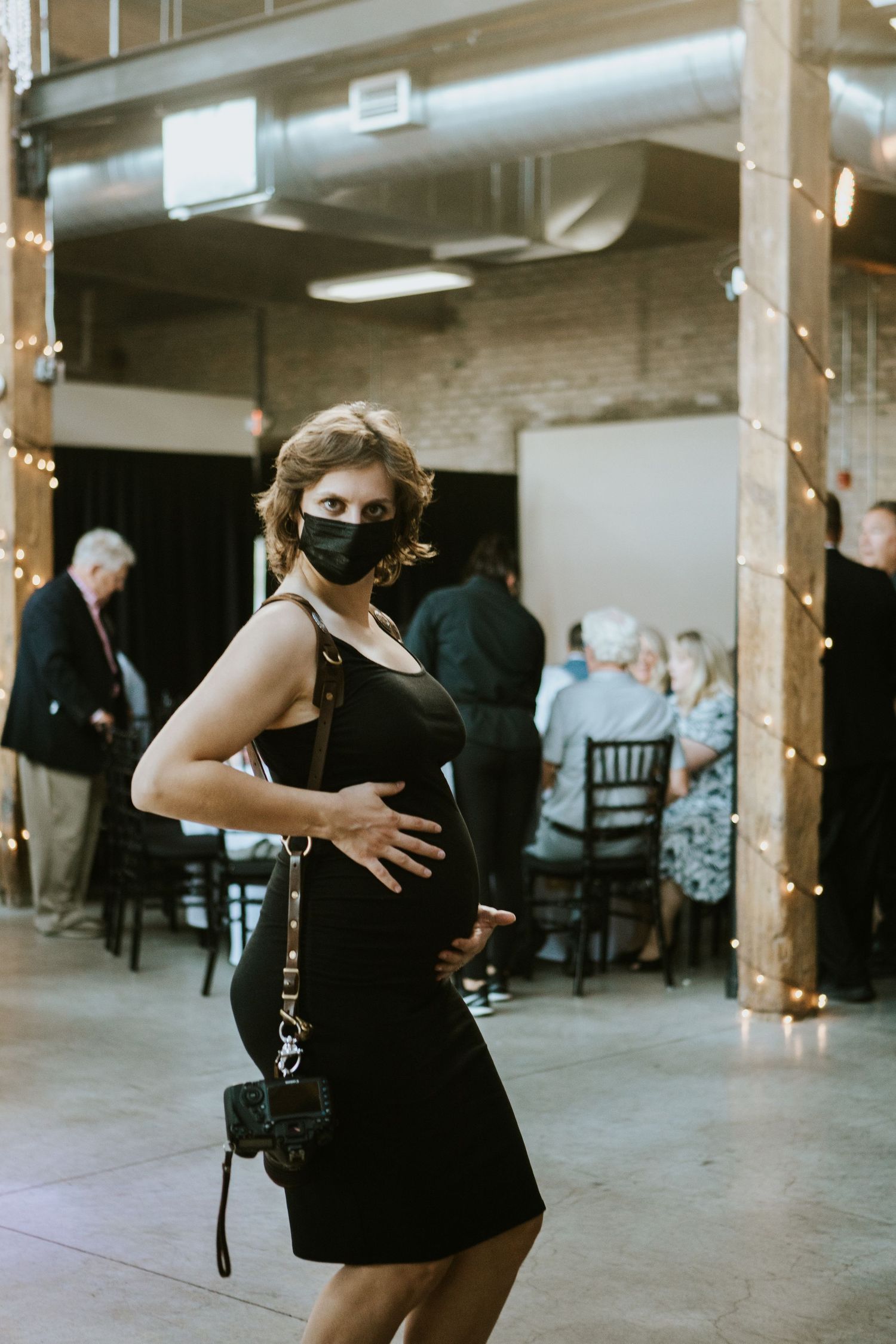 Guests dancing at an indoor event with string lights and brick walls.