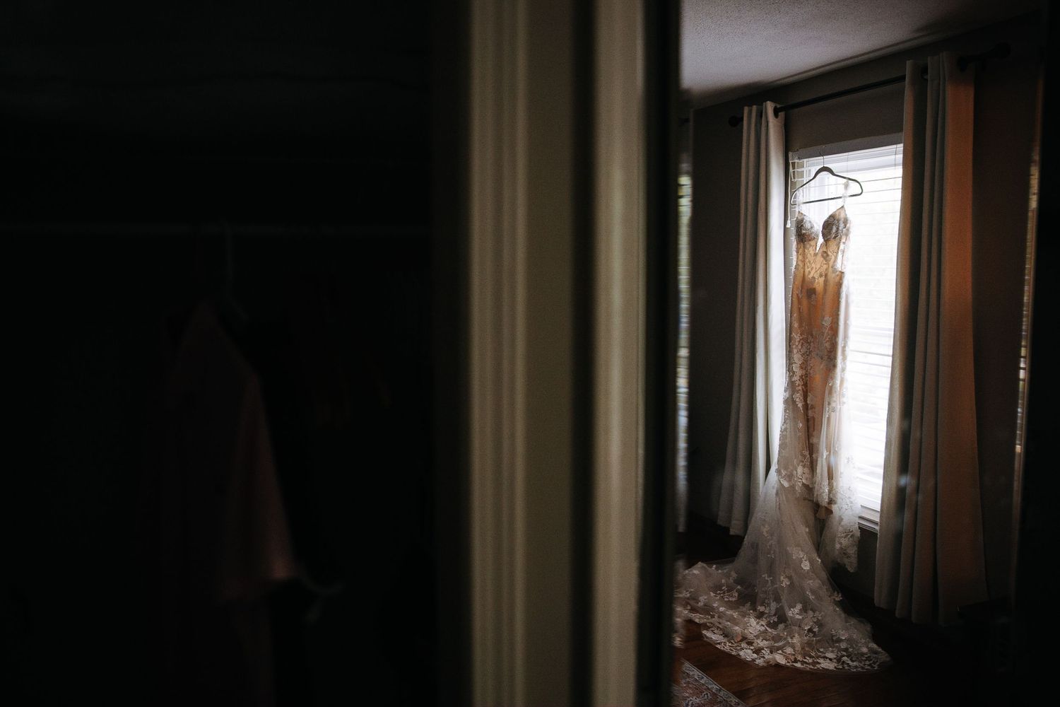 Wedding dress silhouette framed in doorway with natural window light.