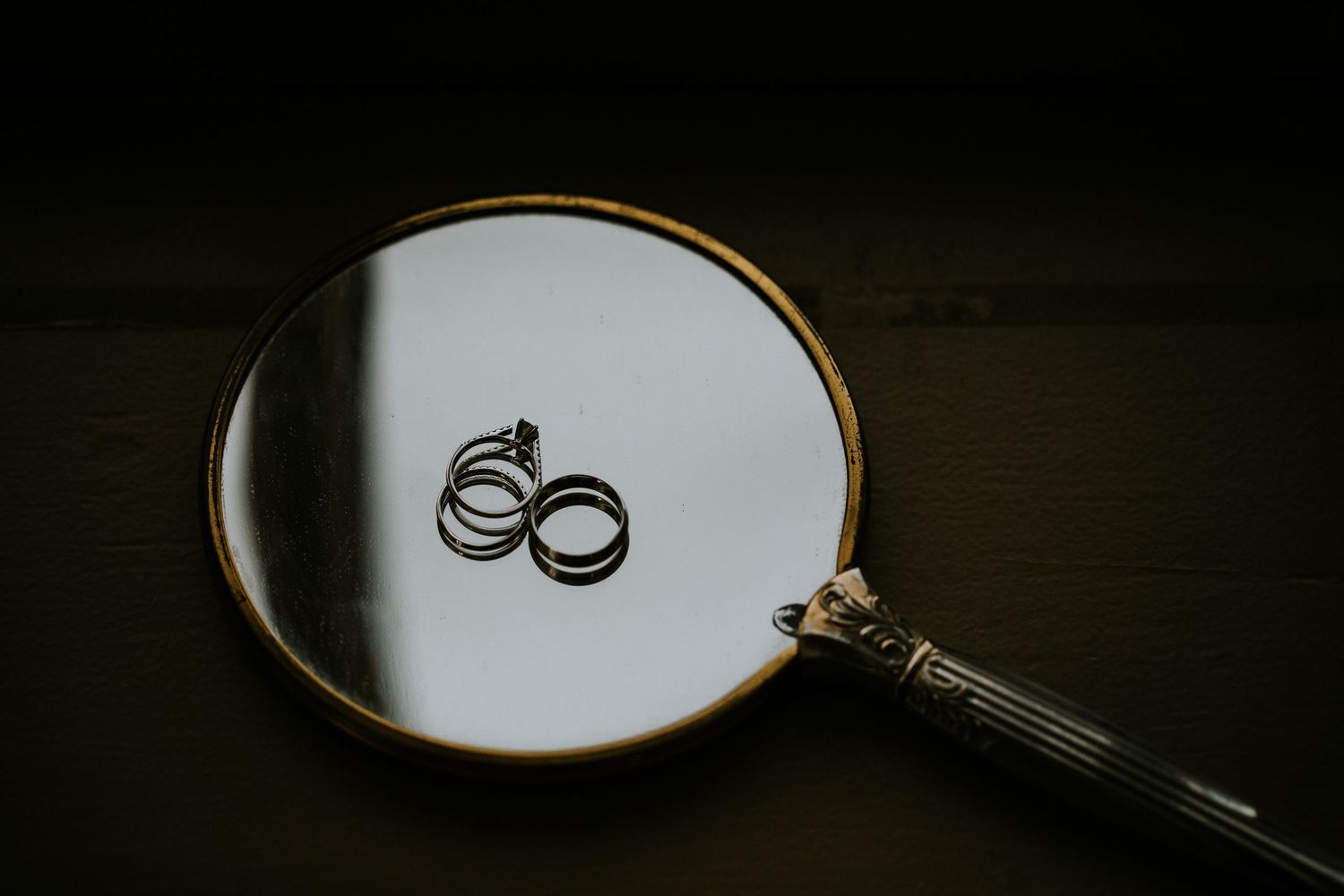 Wedding rings photographed in dramatic lighting with artistic composition.