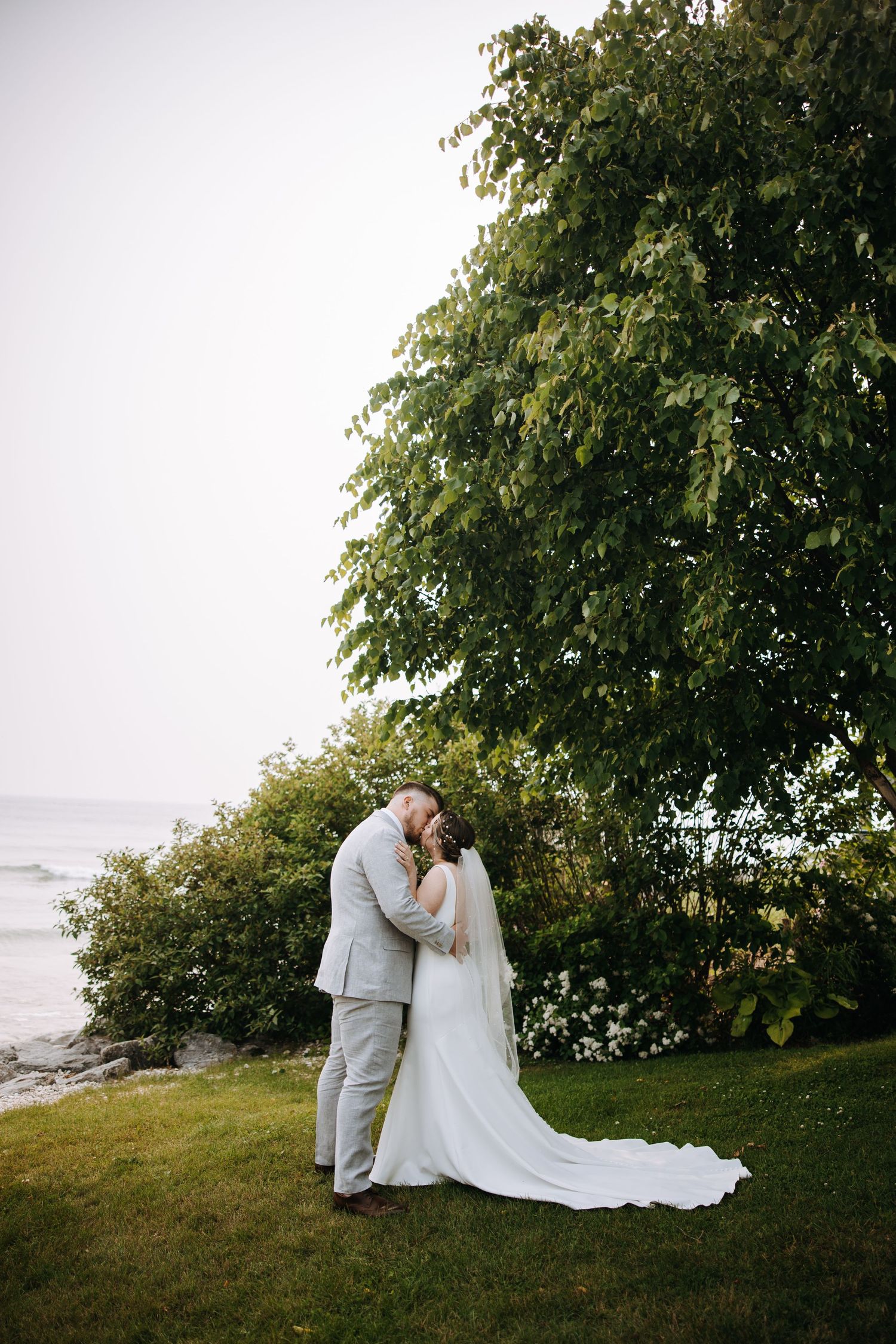 A couple shares an intimate moment during their outdoor coastal wedding photoshoot.