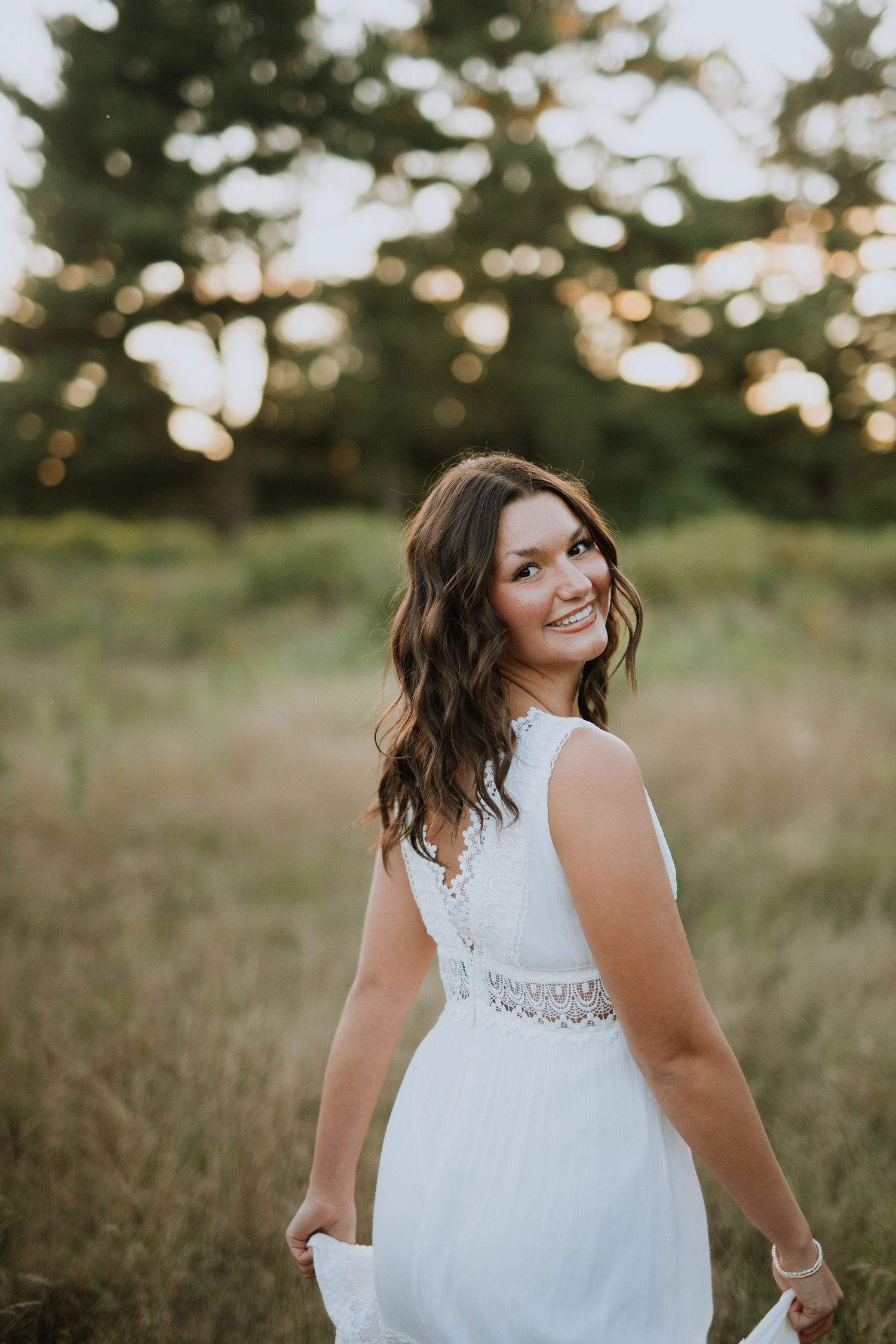 A sleeveless white dress with lace details captured in golden hour lighting outdoors.