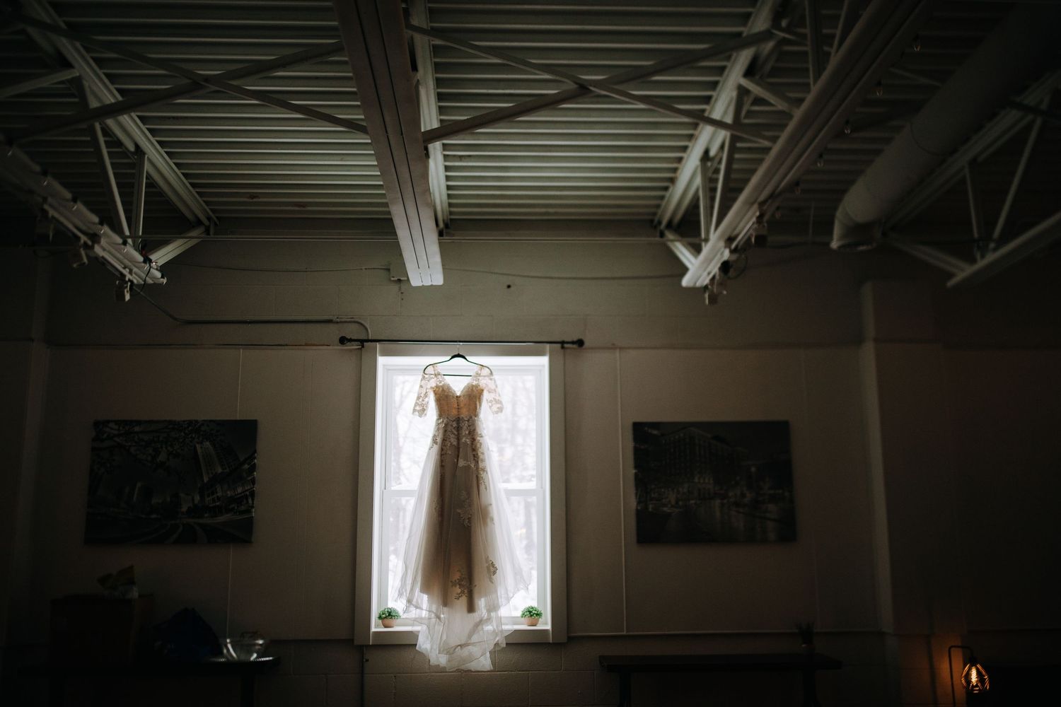 Wedding reception venue interior with exposed ceiling beams and hanging string lights creating a rustic ambiance.