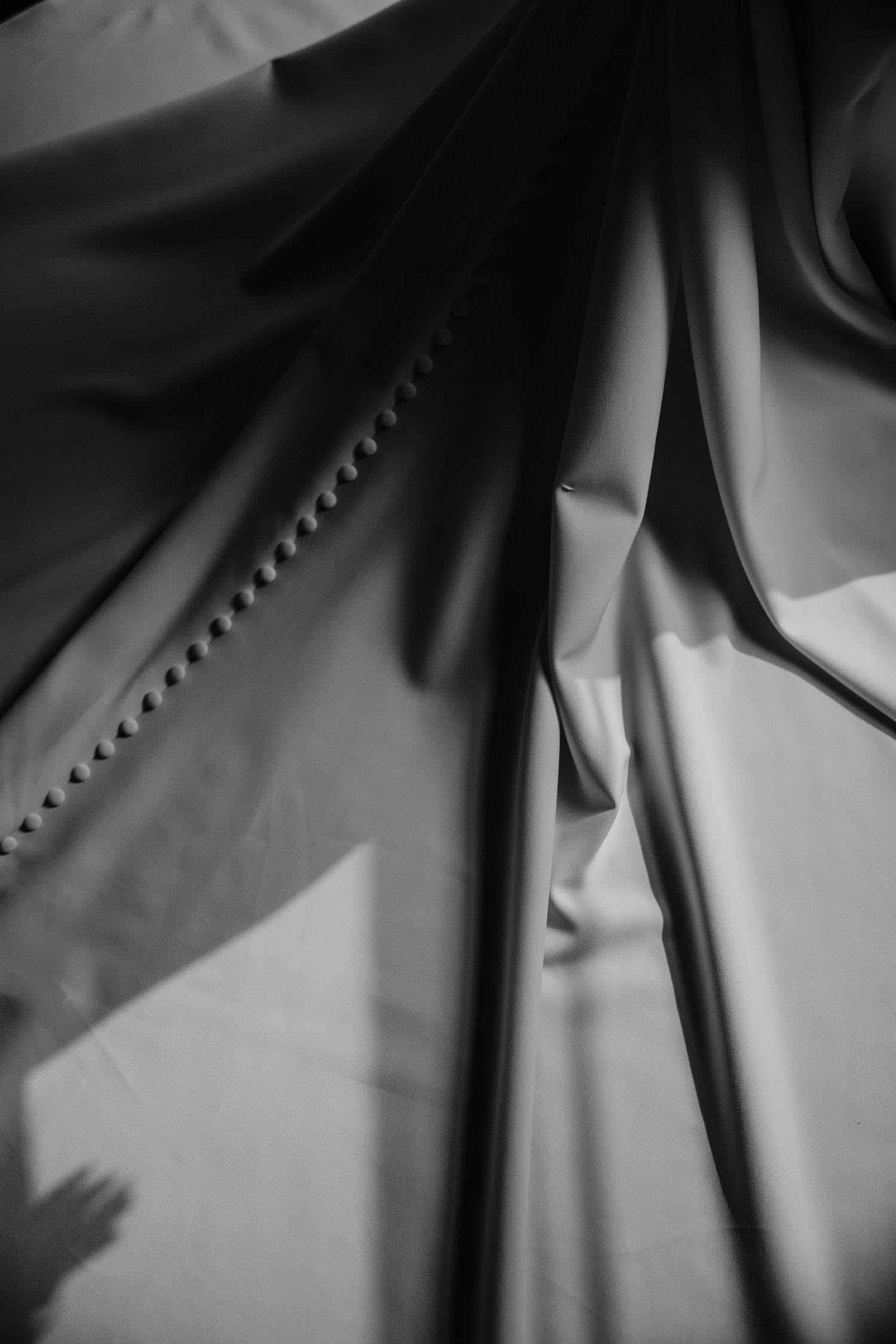 Abstract black and white detail of wedding dress buttons creating dramatic shadows.