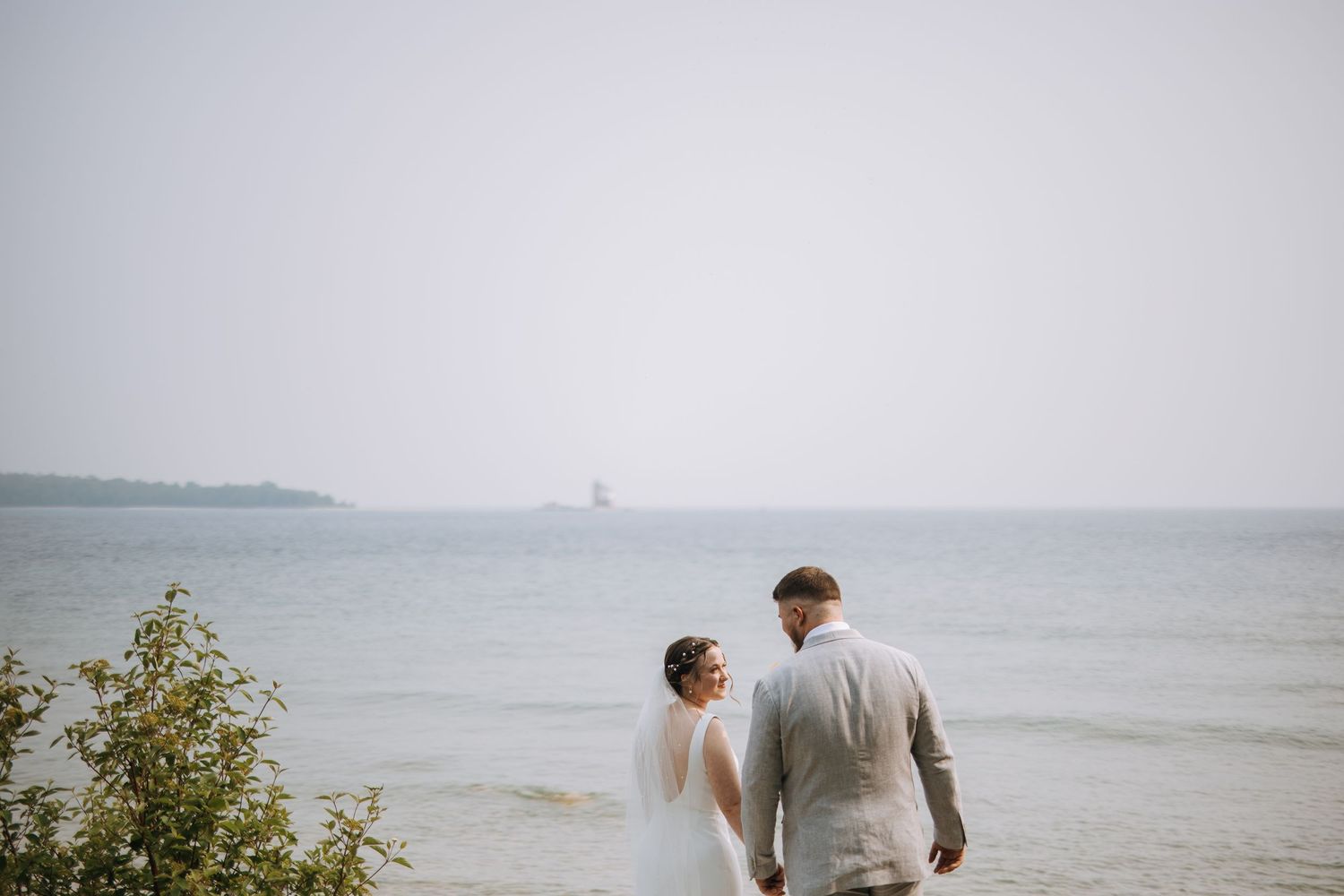 Scenic coastal wedding photoshoot with ocean and cloudy sky in background.