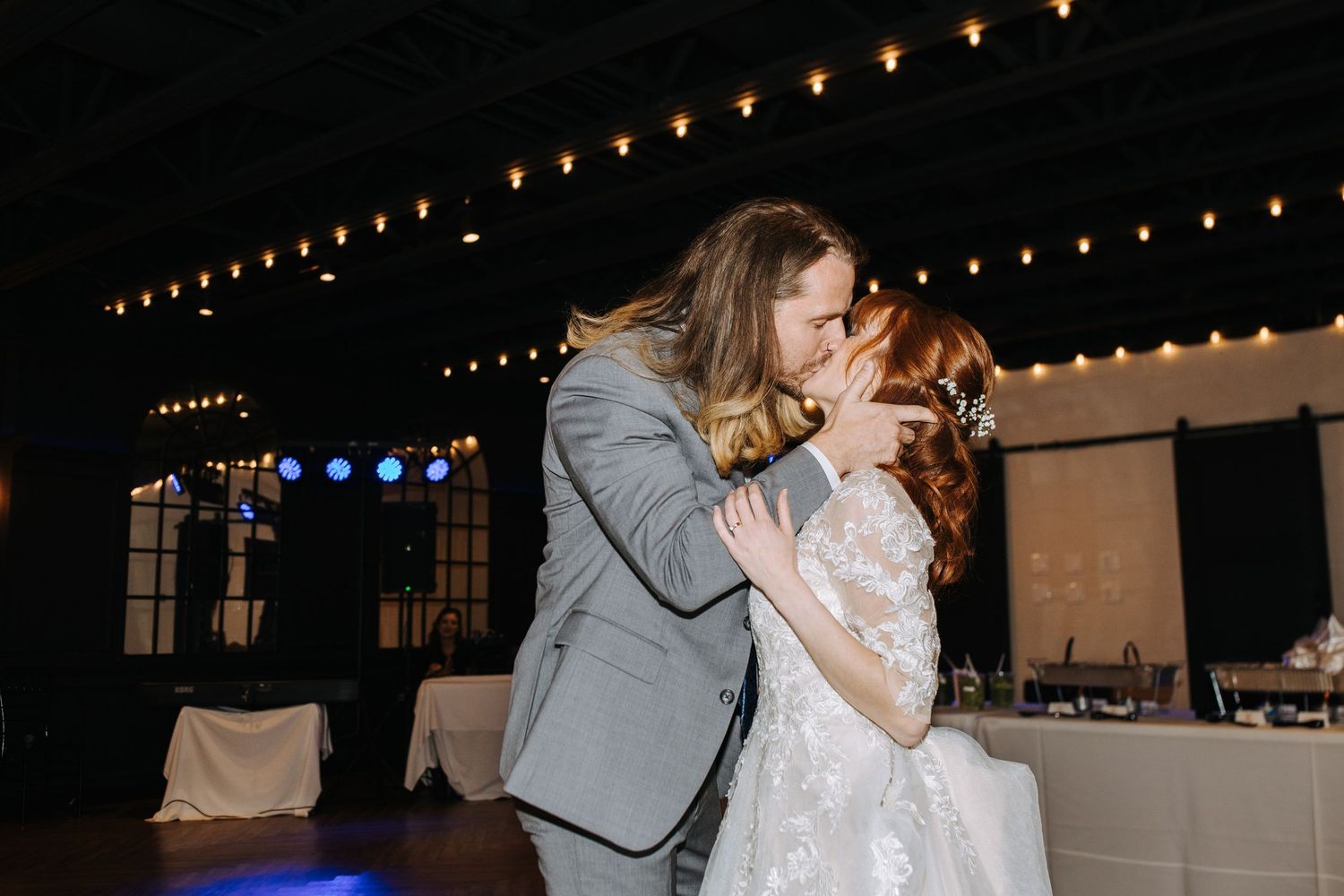 Dancing couples at a wedding reception under warm string lights.