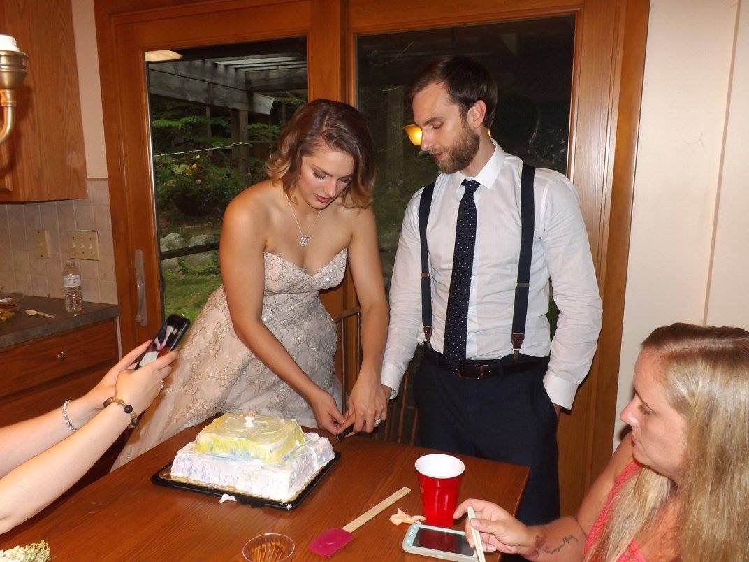 People gathered around table during celebration with cake.