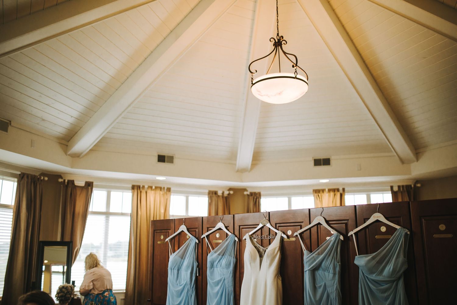 Rustic wooden beams and white planks line the vaulted ceiling of a cozy interior room with pendant lighting.