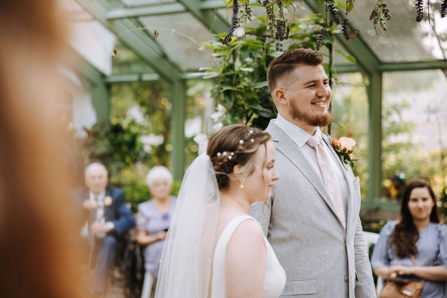 Intimate wedding ceremony moment captured in a sunlit greenhouse setting.