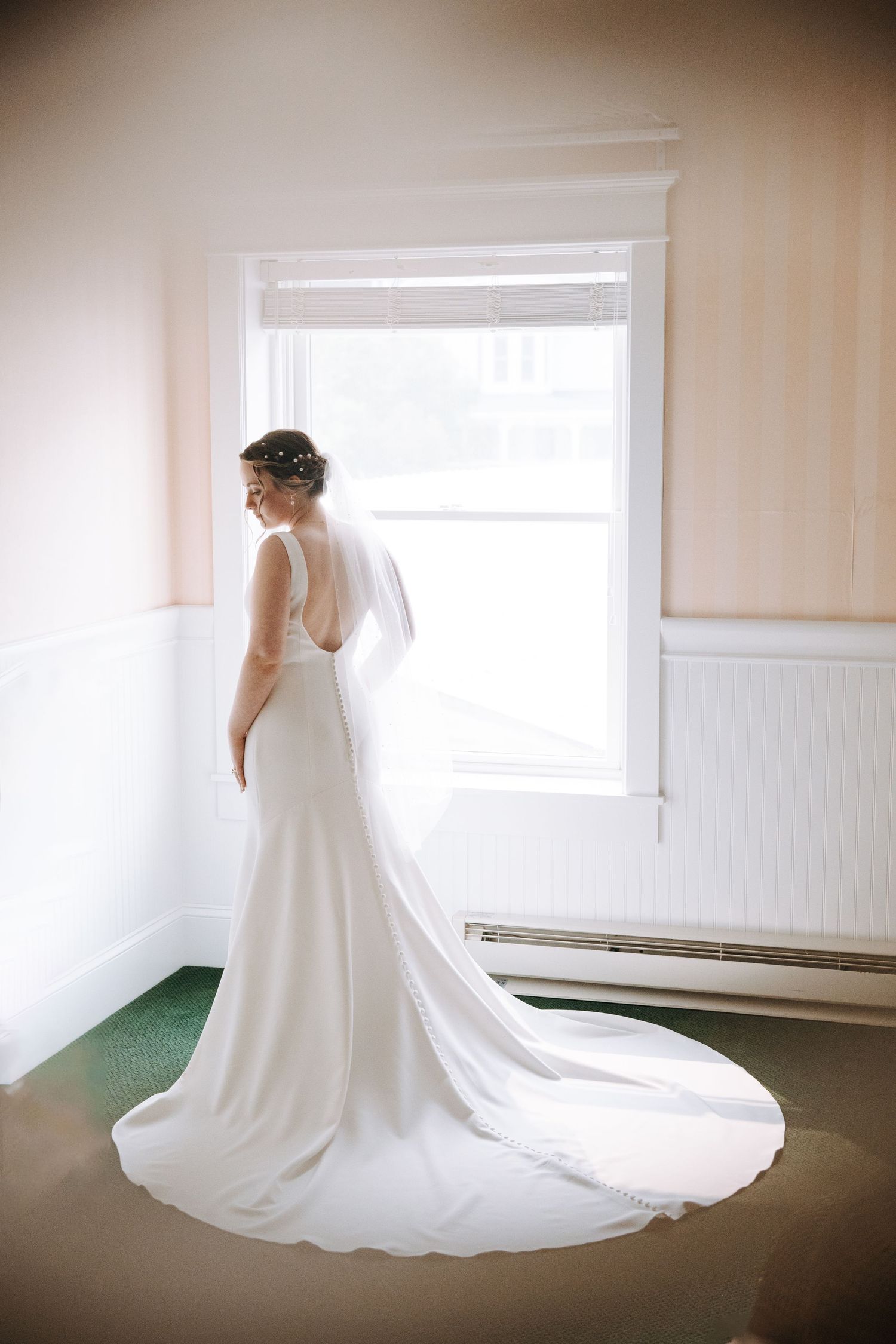 Elegant white wedding dress with long train photographed in natural window light.