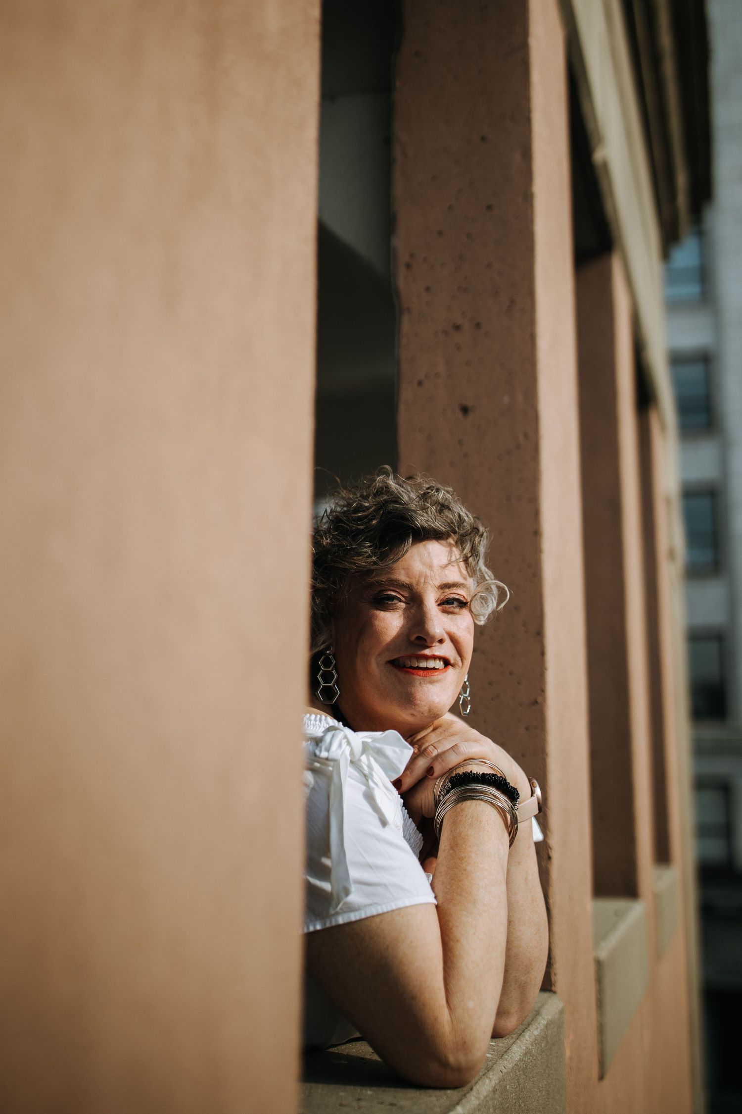 Candid portrait series showing joyful expressions against a neutral architectural background.